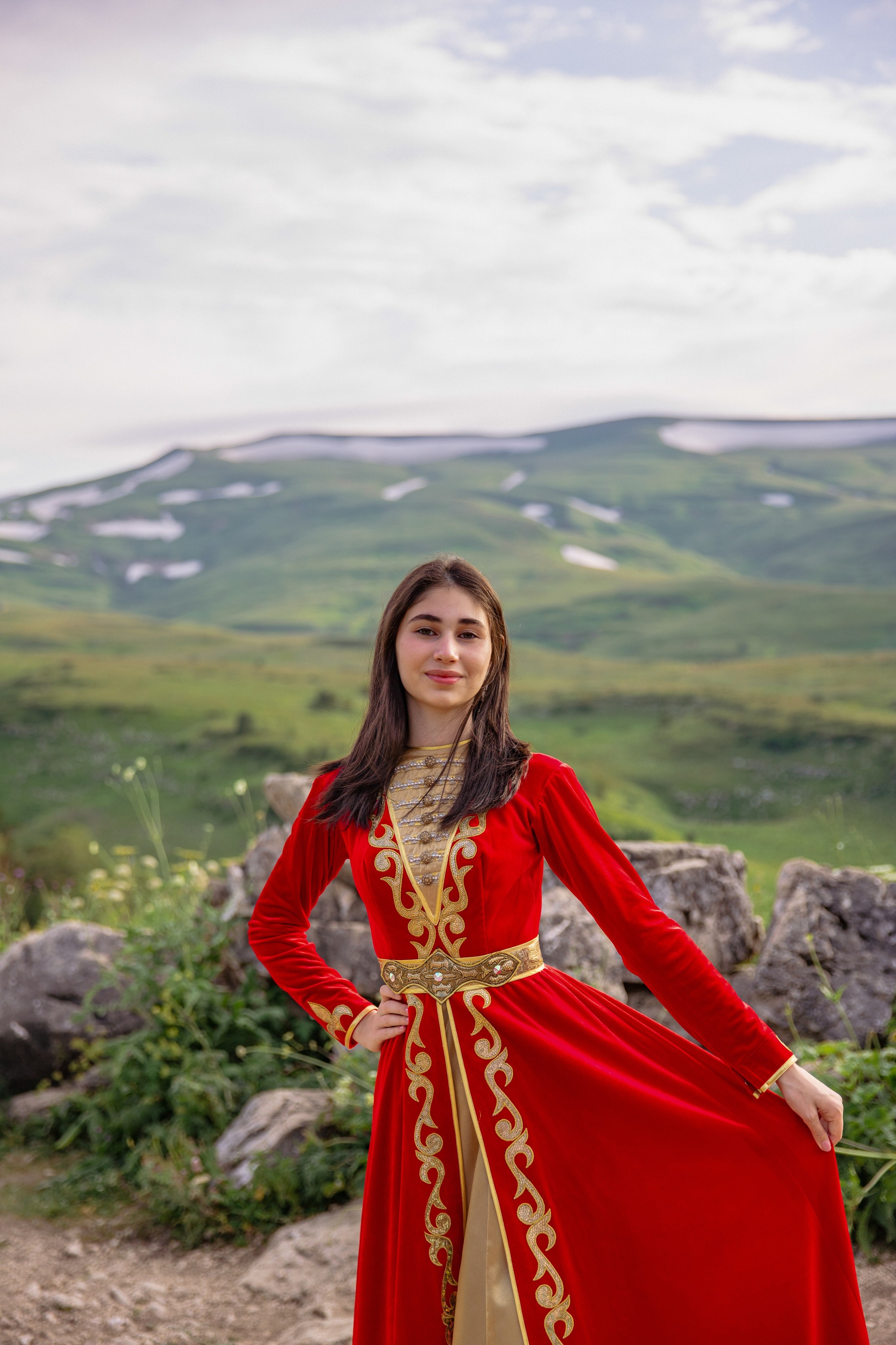 Средний план: Красивая представительница адыгейской культуры в традиционном наряде  на фоне громких гор