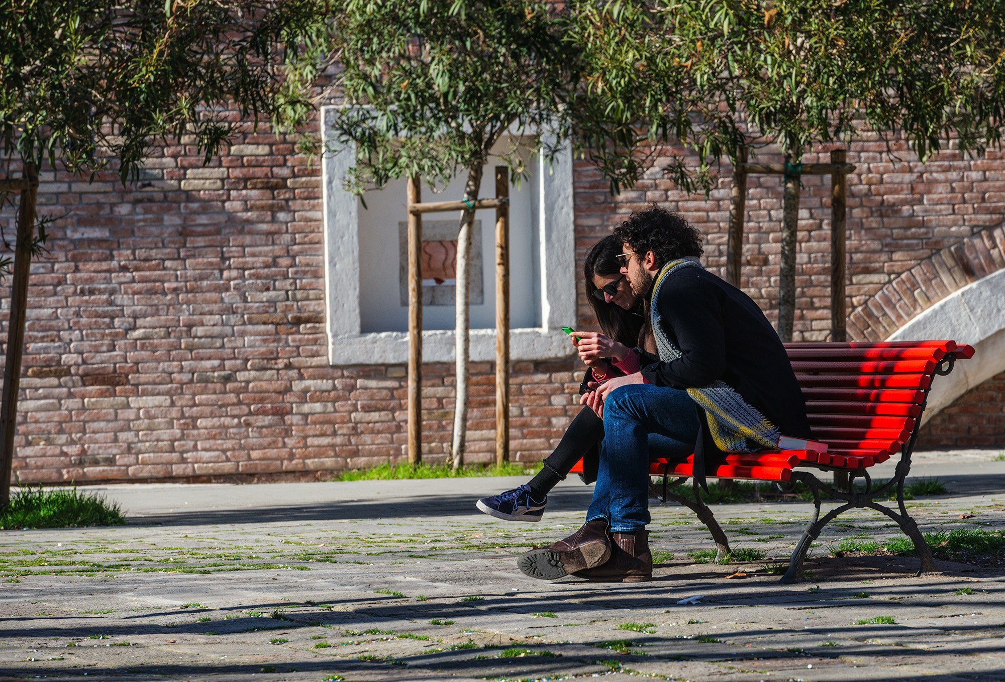 Пара сидит на красной скамейке в Италии во время фотопрогулки.