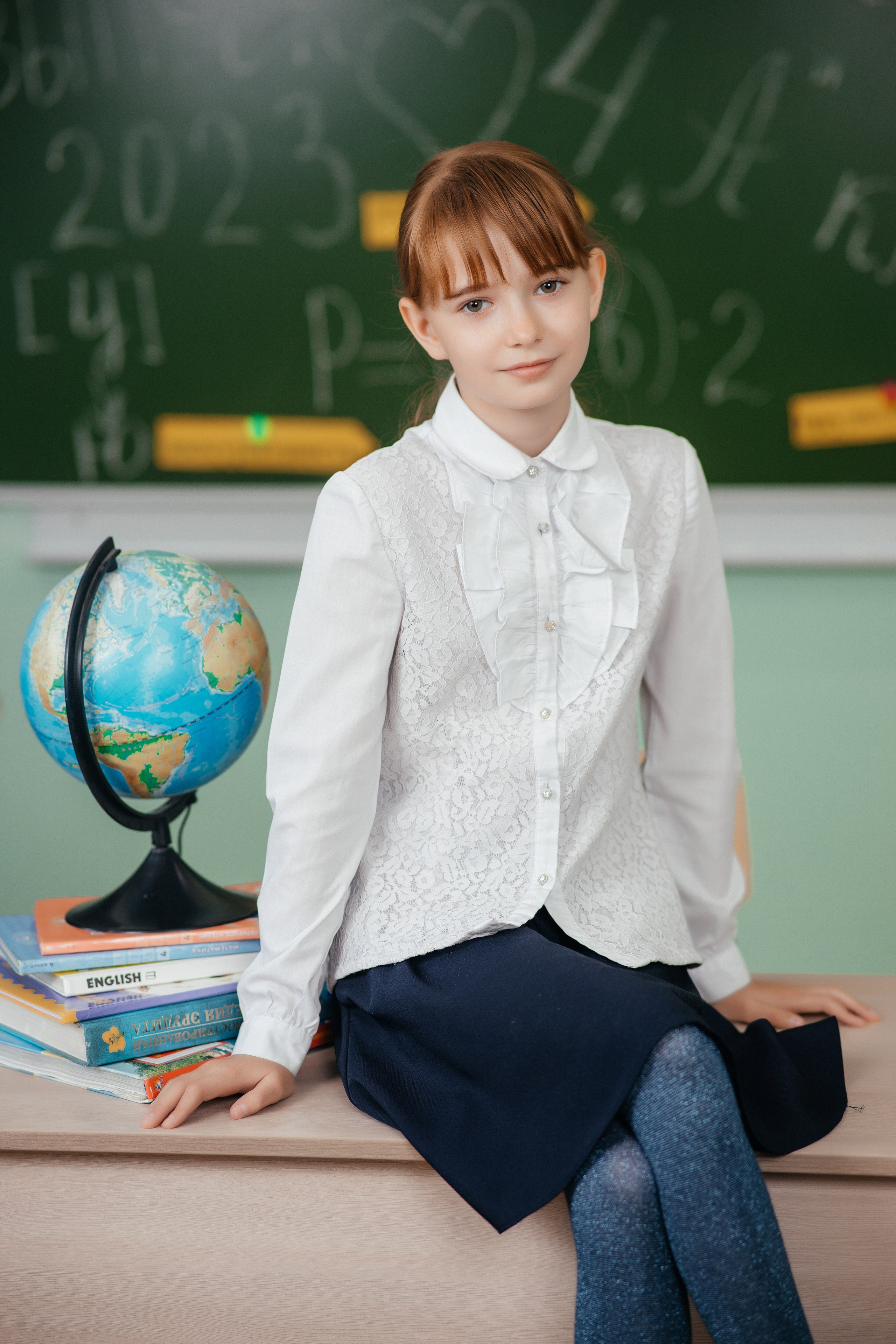 Выпускница сидит на парте на фотосъемке для выпускного альбома г. Усть-Каменогорск