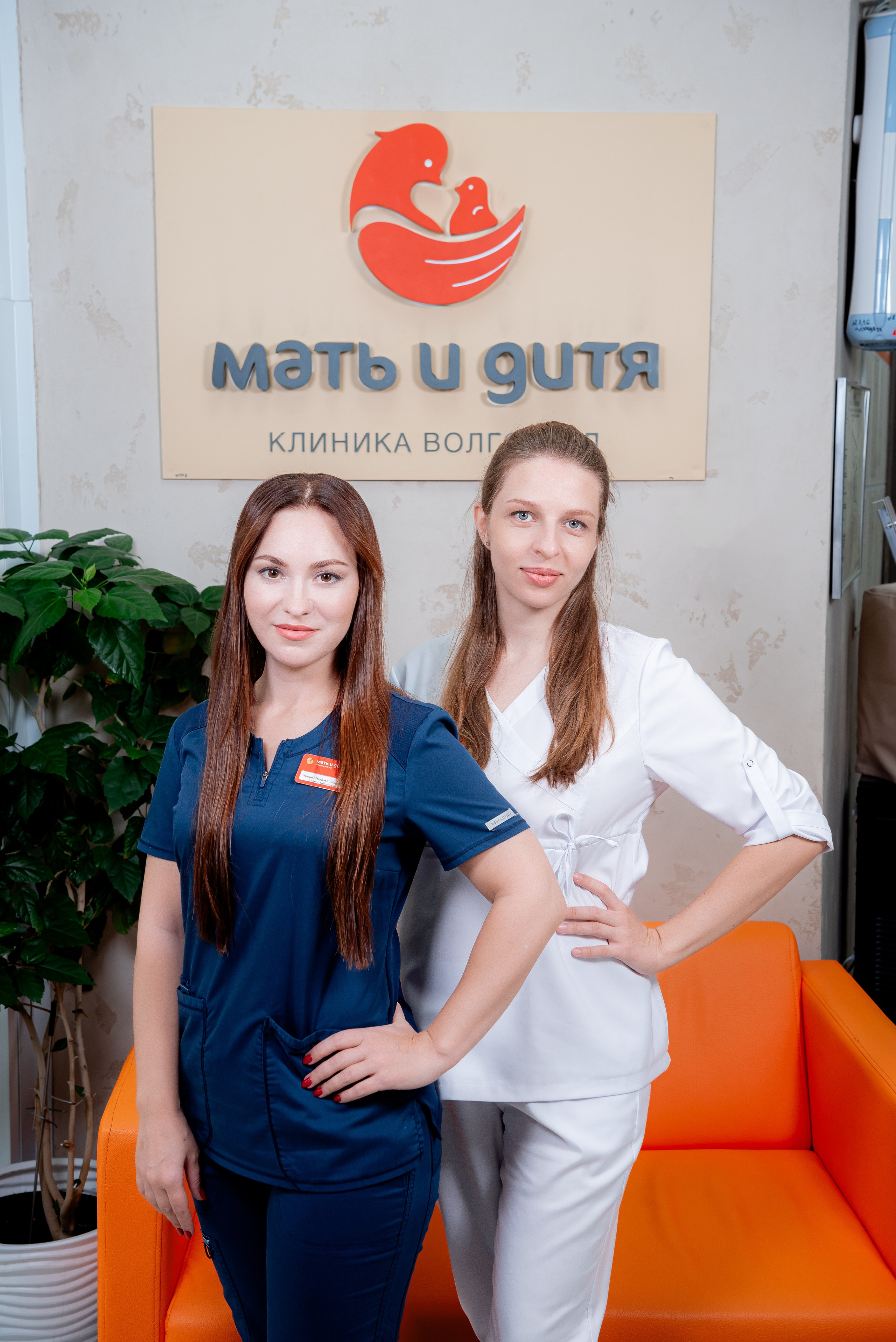 Групповой портрет команды врачей медицинской клиники на фоне логотипа в холле.