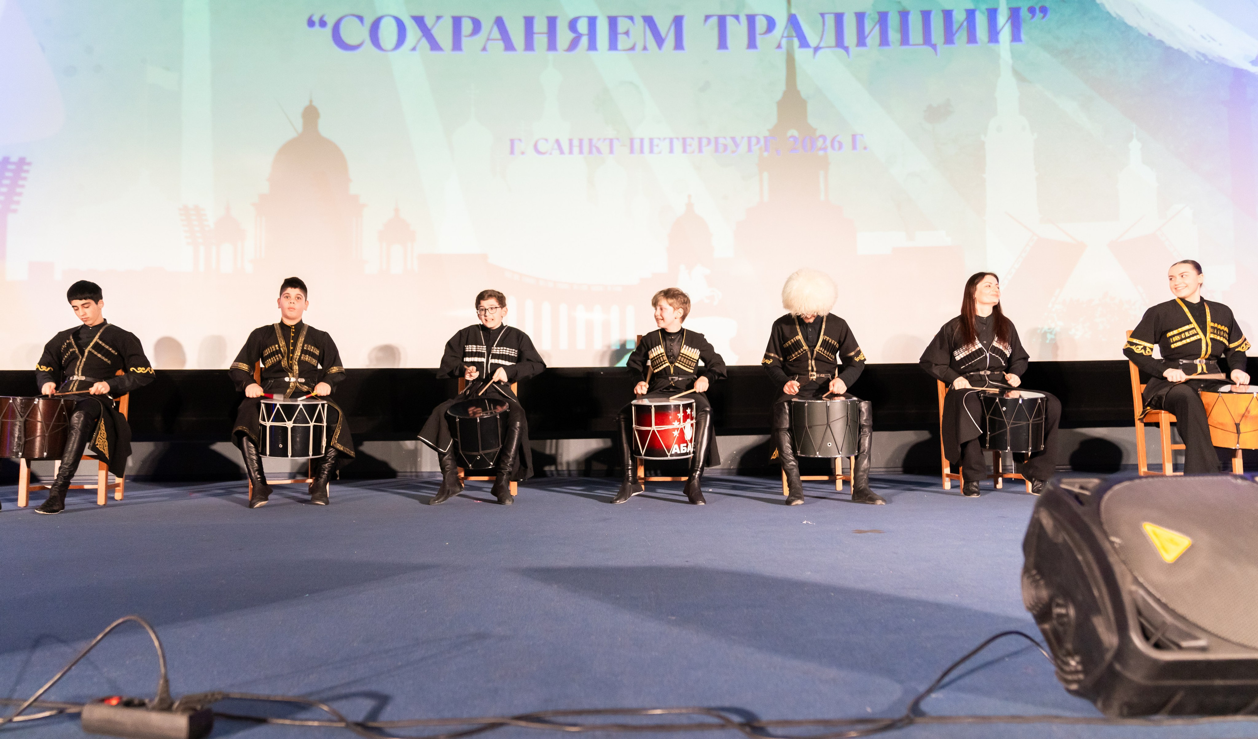 Большой ансамбль барабанщиков (7 человек) в традиционных костюмах на сцене фестиваля «Сохраняем традиции», Санкт-Петербург 2026 год. Фото Евгения Мальцева.