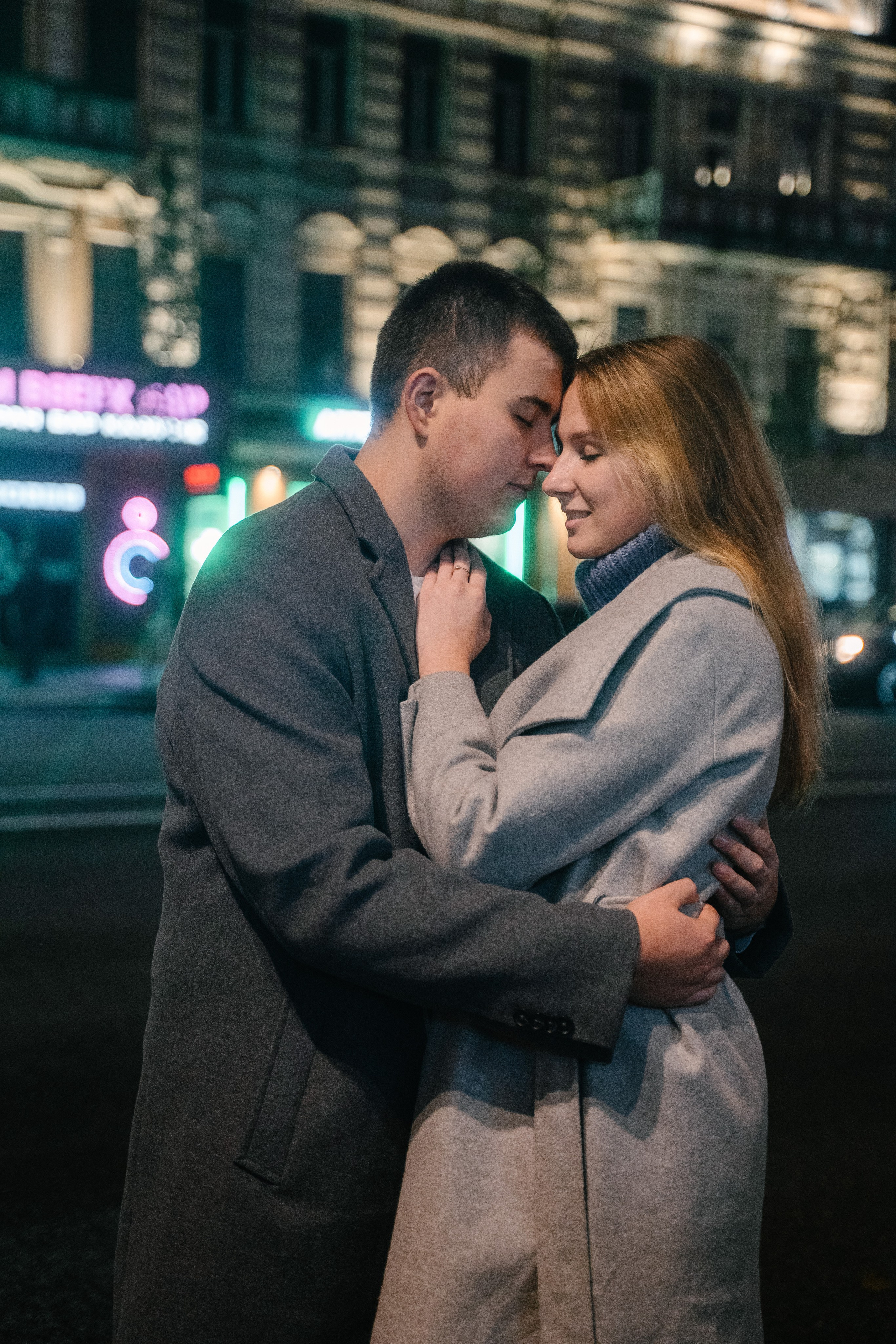 парень с девушкой стоят у дороги в пальто и обнимаются