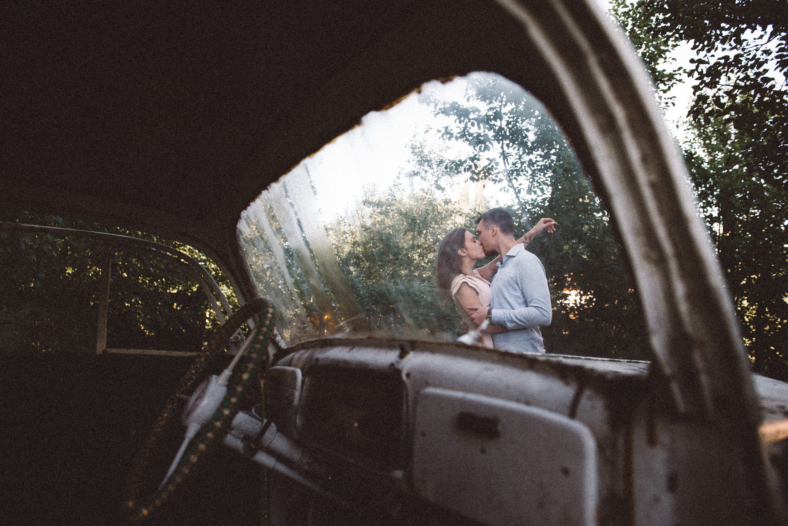 Парень и девушка целуются. Фотография сделана сквозь ретро автомобиль