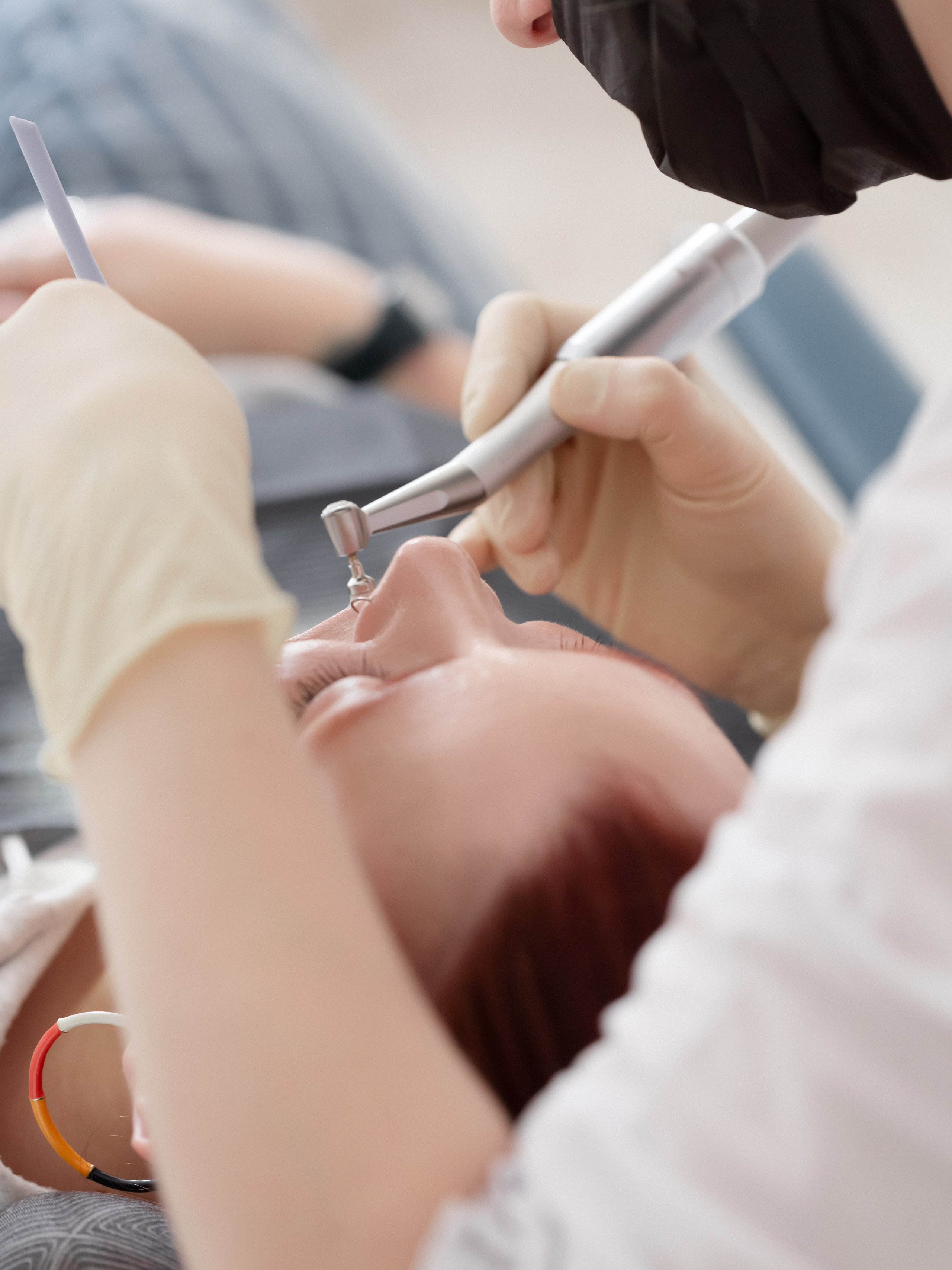 врач-стоматолог работает с пациентом: процесс лечения в перчатках и маске