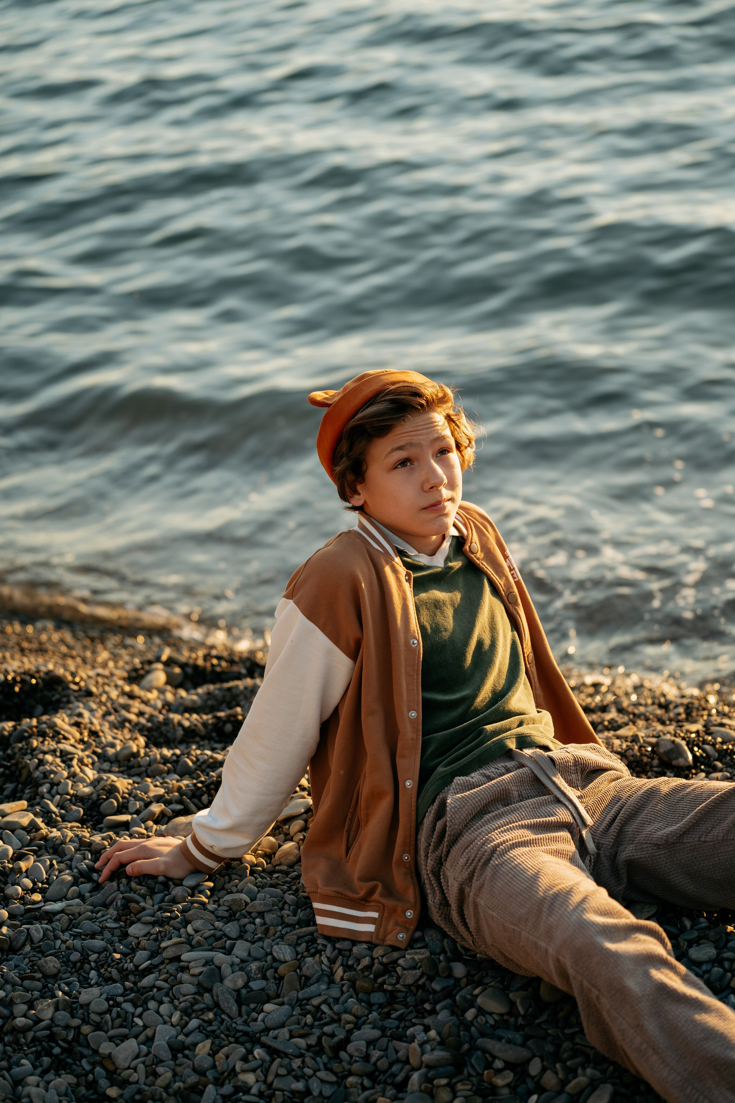 Игра с детьми во время фотосессии в Новороссийске. Папа подбрасывает дочку, а сын-подросток улыбается. Живые и веселые кадры у воды.