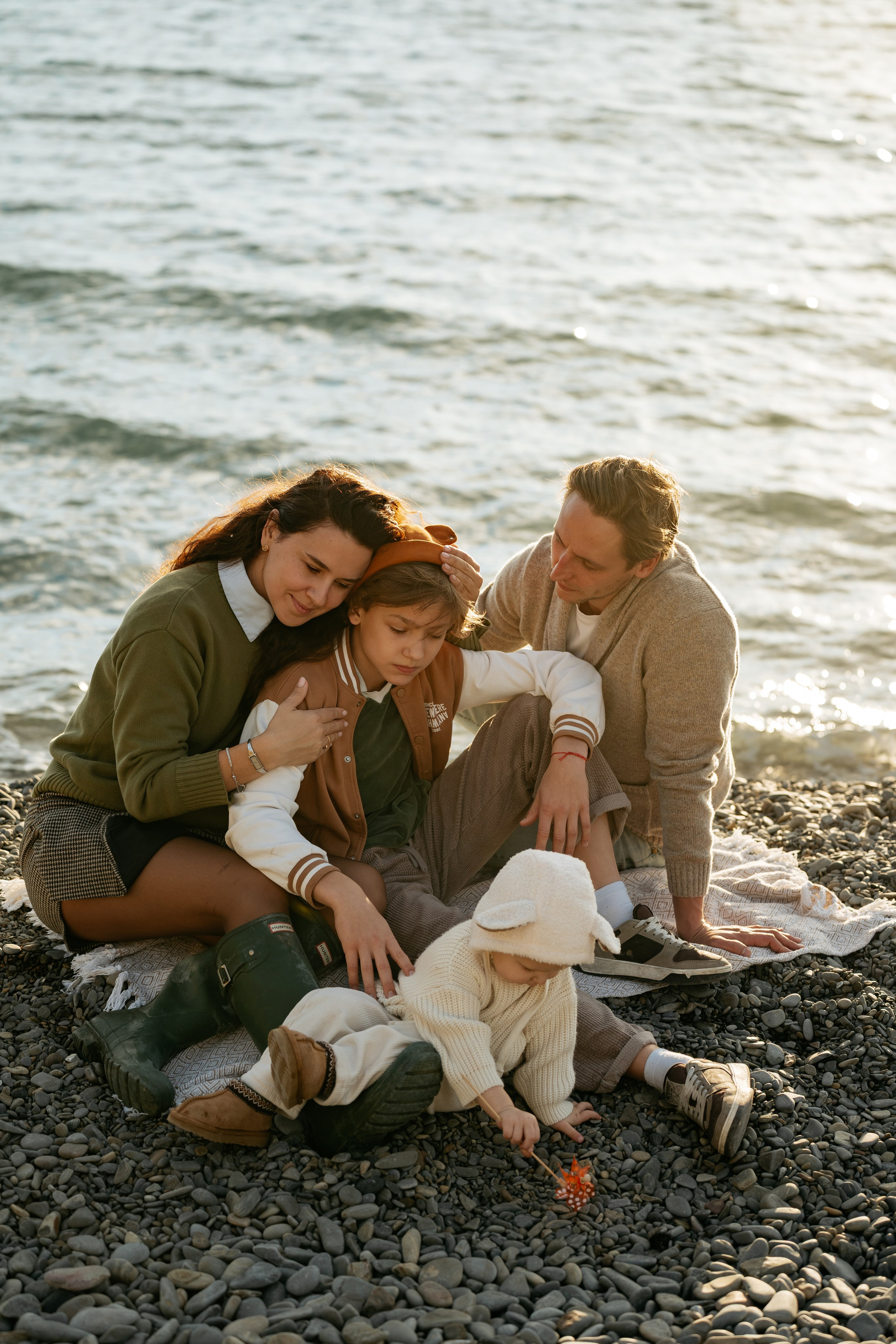 Крупный план: счастливые лица семьи после фотосессии в Новороссийске. Все смеются, фон — морской прибой.