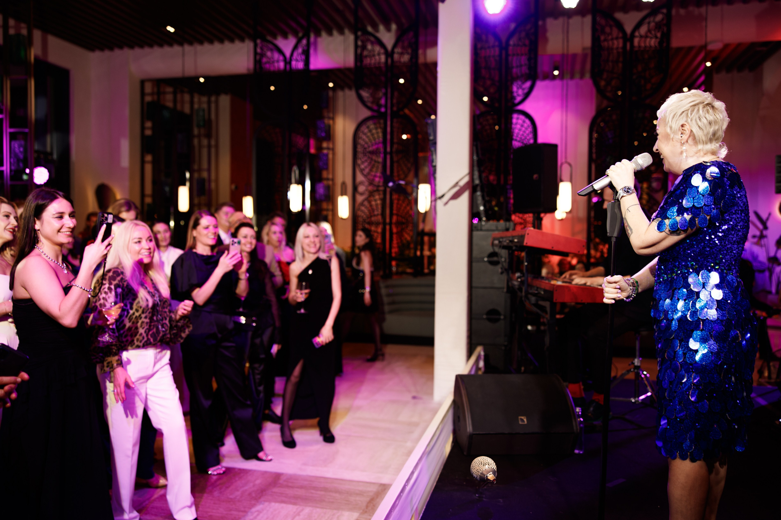 Живой вокал: Певица теона кантридзе в блестящем синем платье выступает перед гостями.