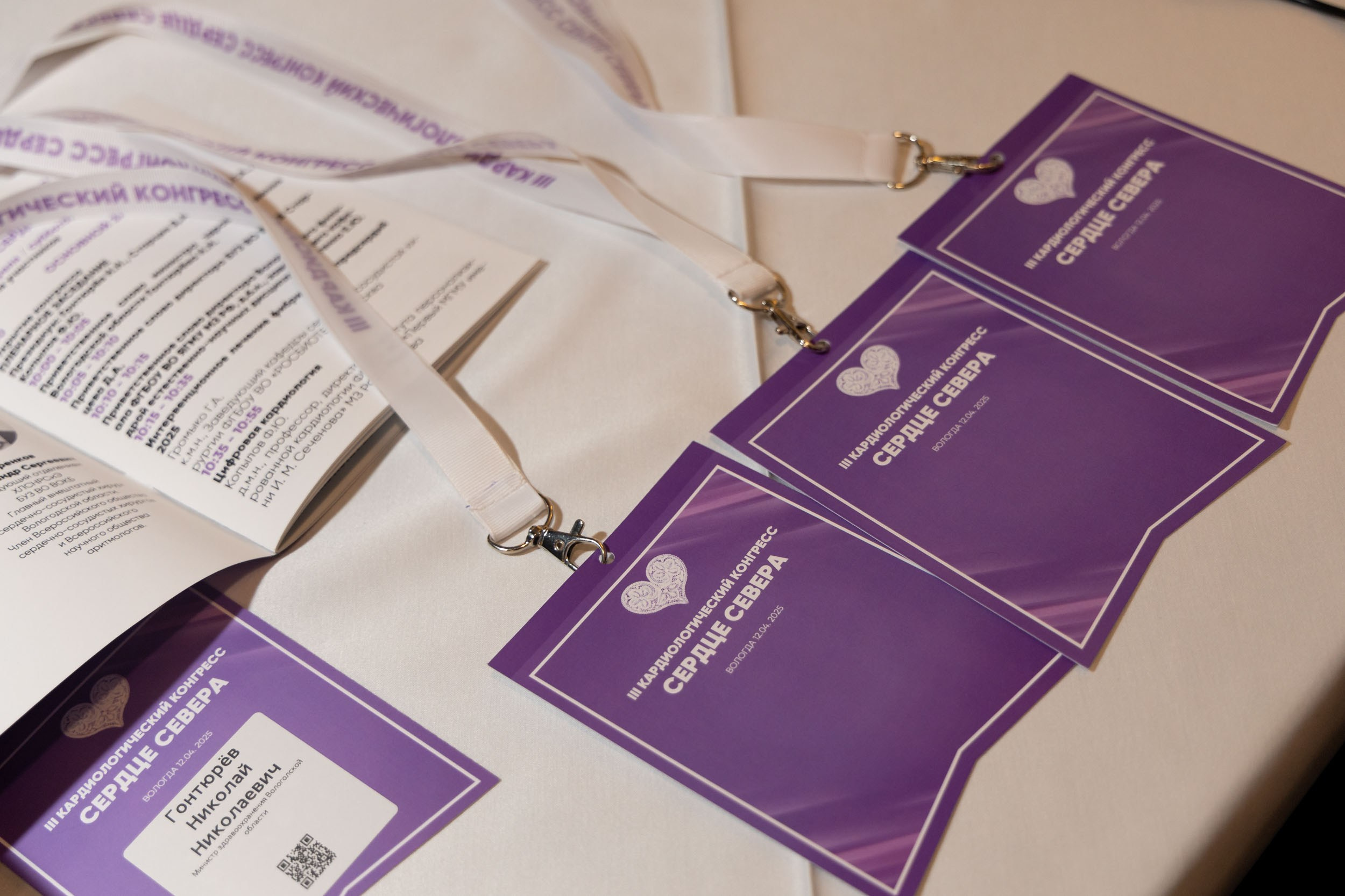 Фиолетовый бейджи с белыми лентами на столе.