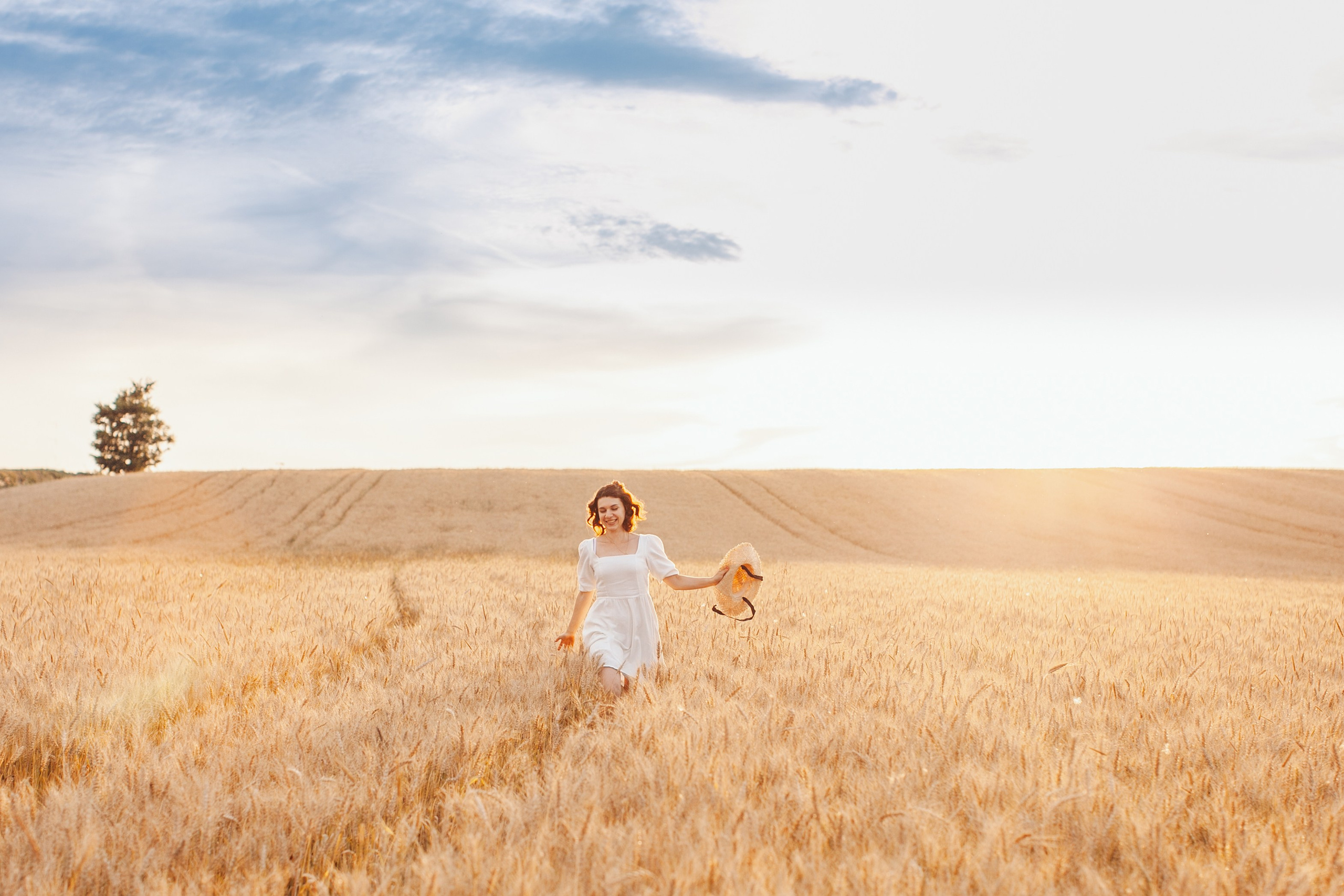 Пейзаж летом желтое поле и синее небо на закате. девушка бежит улыбаясь