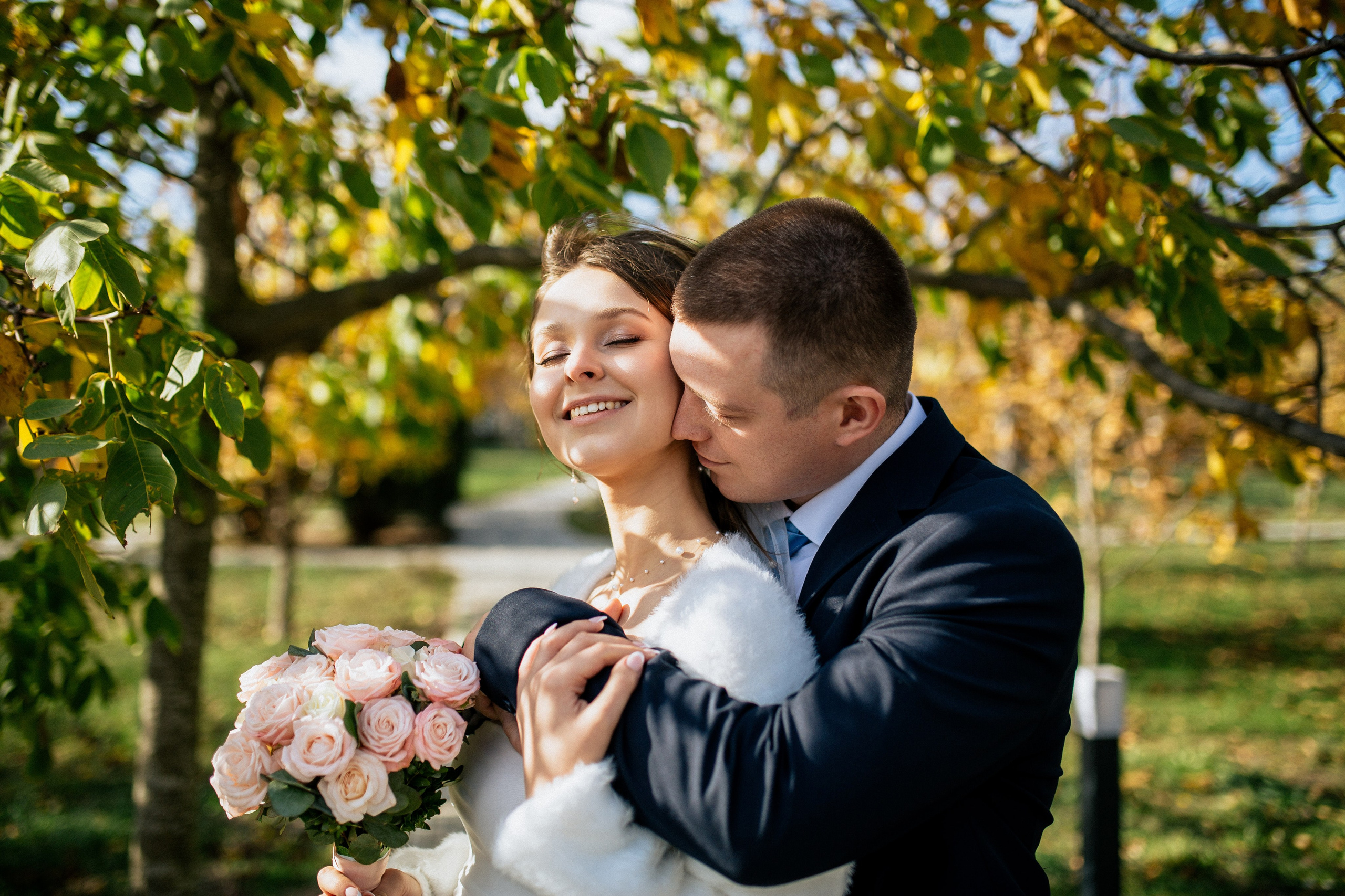 Счастливая пара улыбается в тени деревьев Ореховой Рощи.