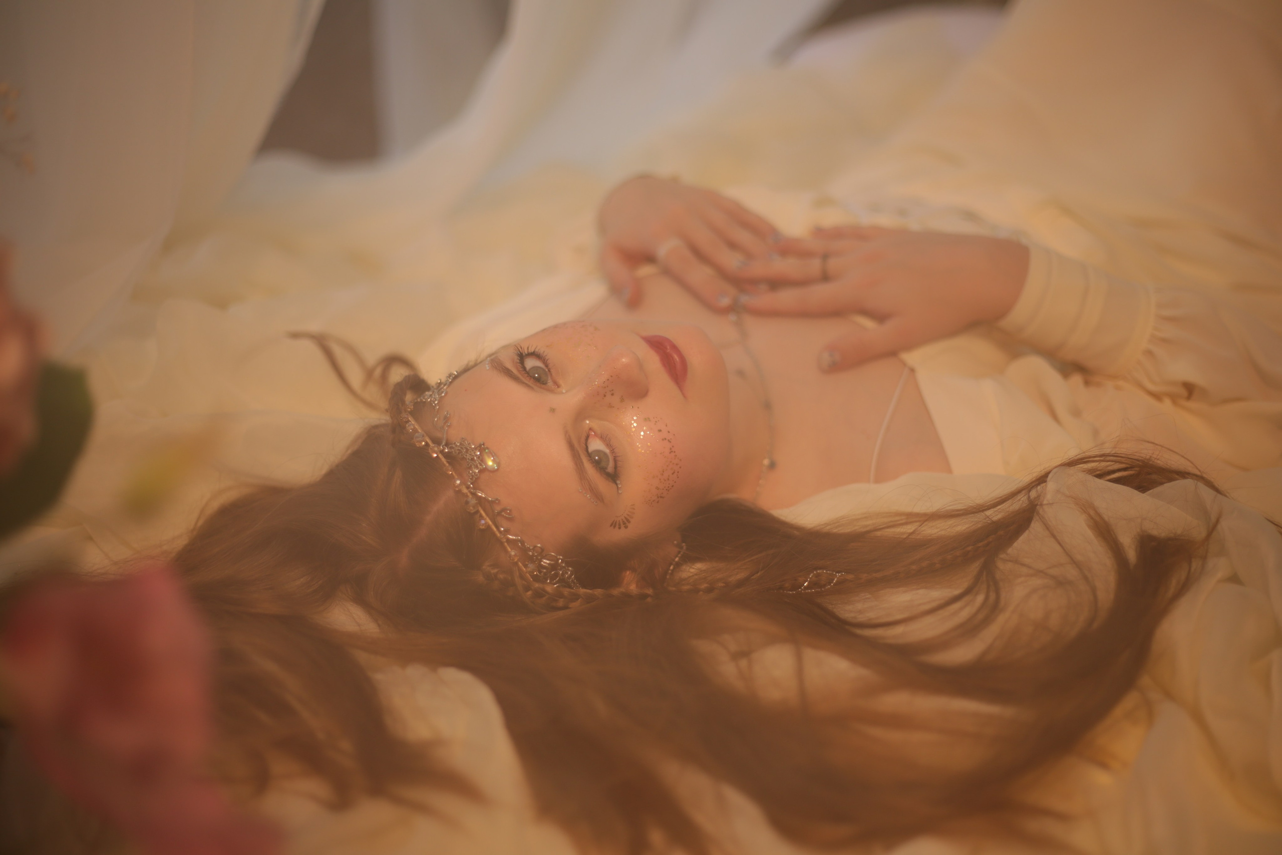 Фотография эльфийки в Перми: девушка в белом платье лежит на кровати под балдахином среди цветов и свечей