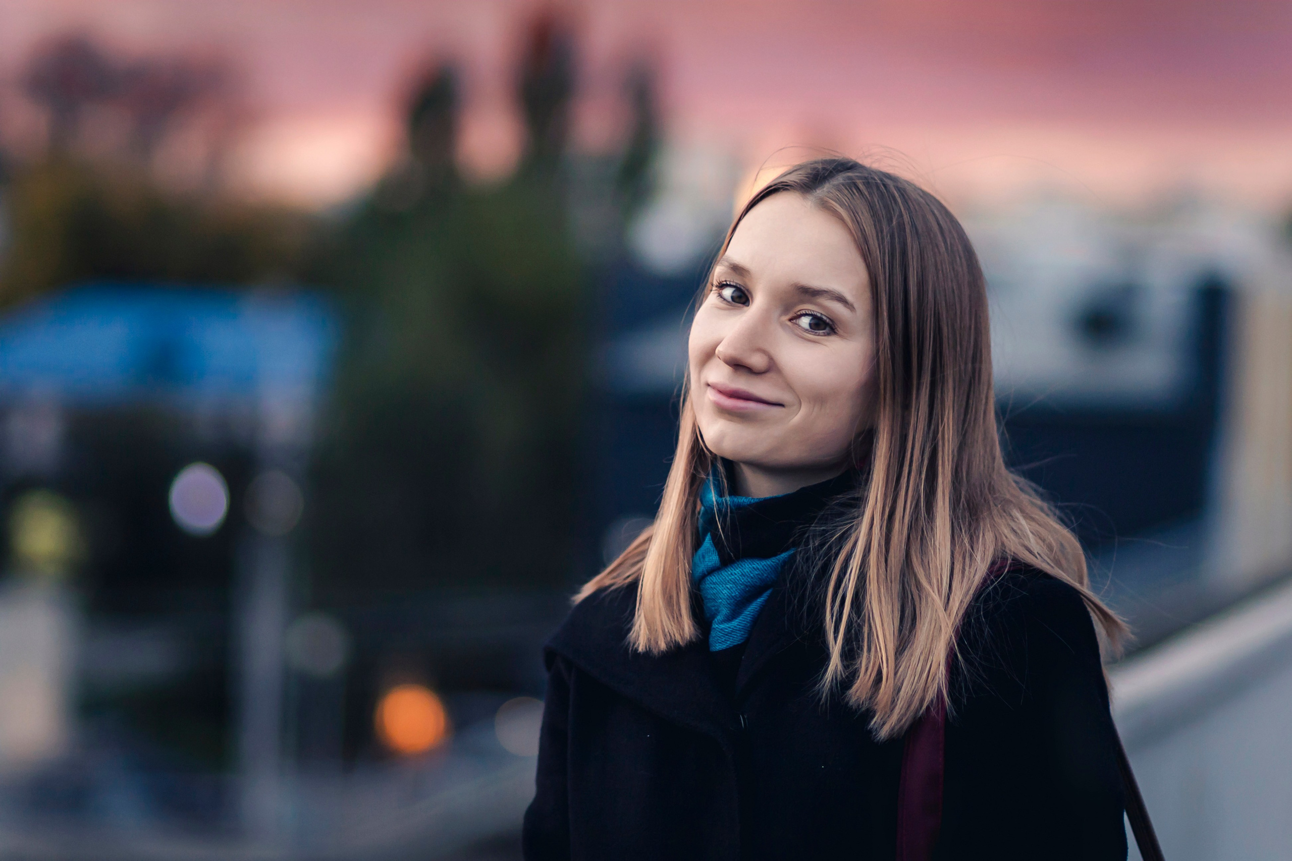 девушка улыбается на фоне вечернего города 