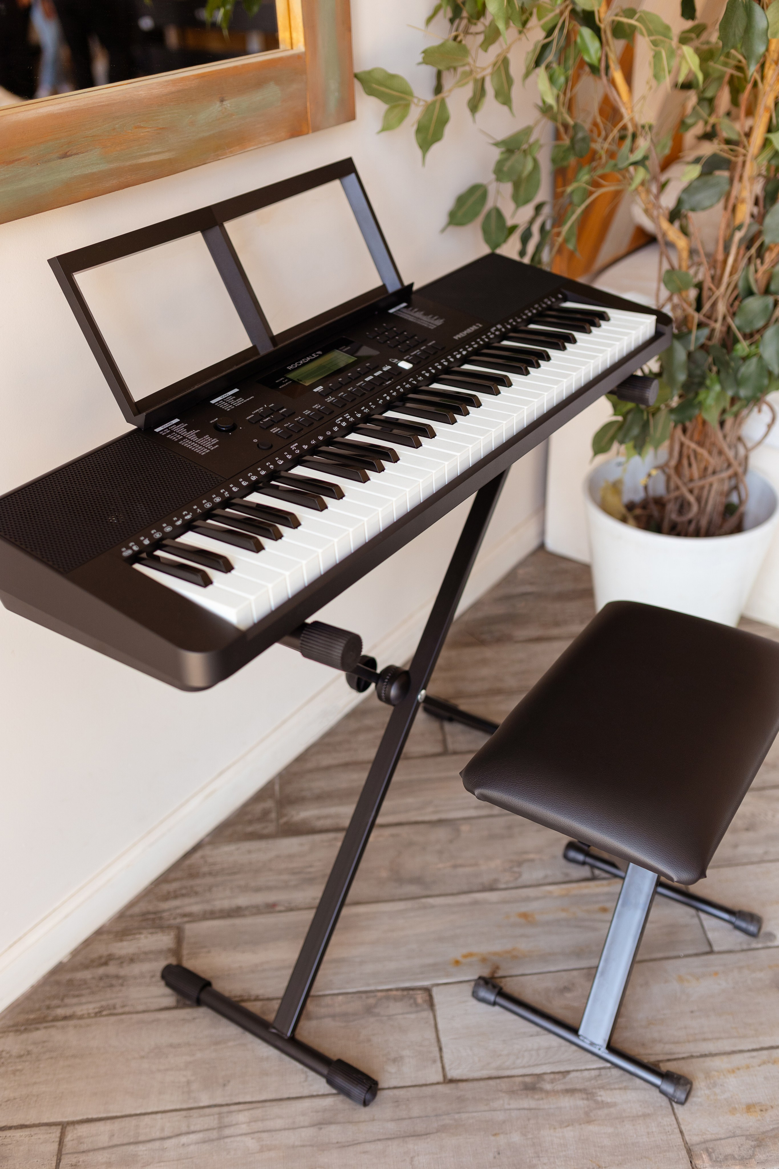 На фото черное электрическое пианино и черный стул. 