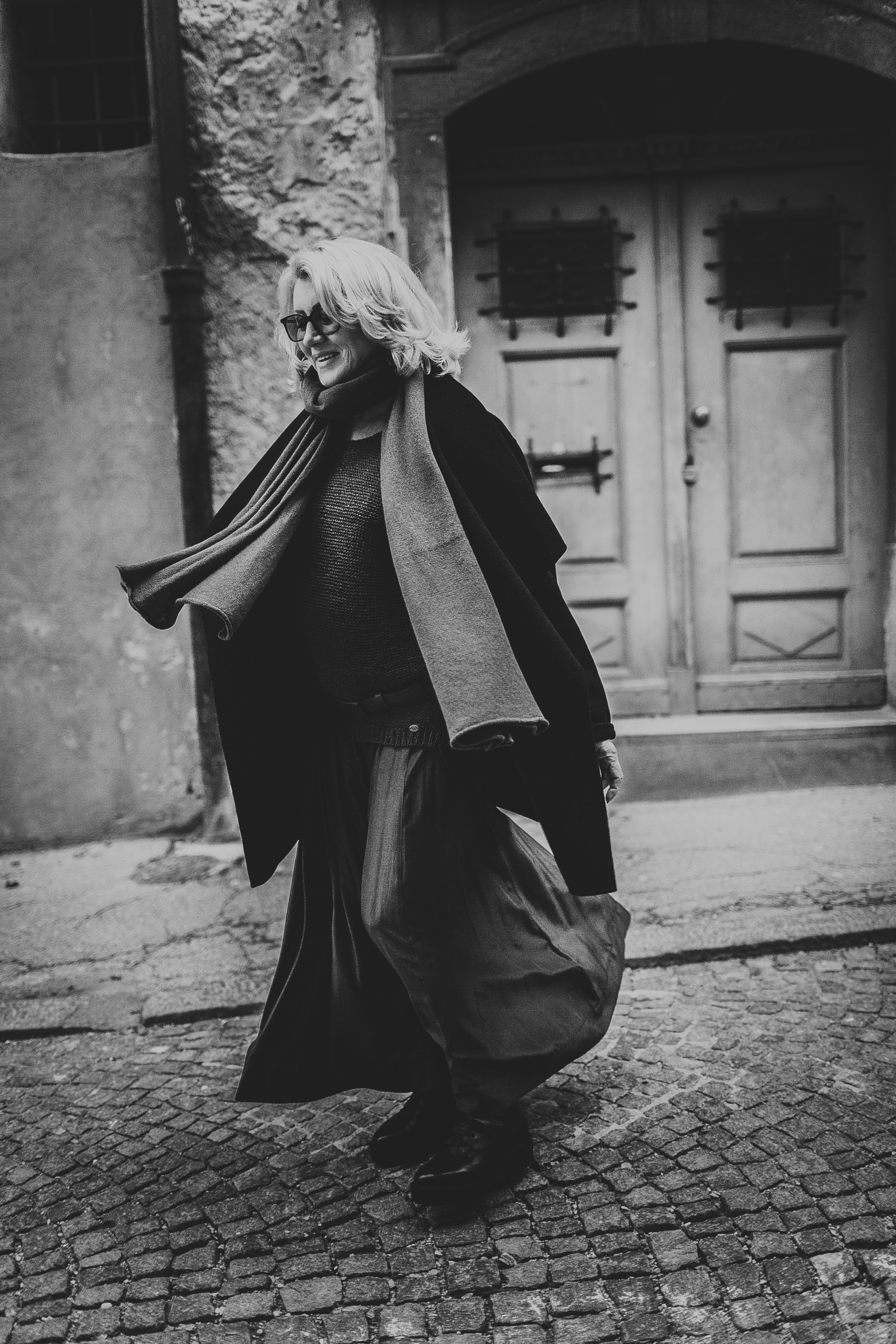 женщина в темном идущая по каменной мостовой