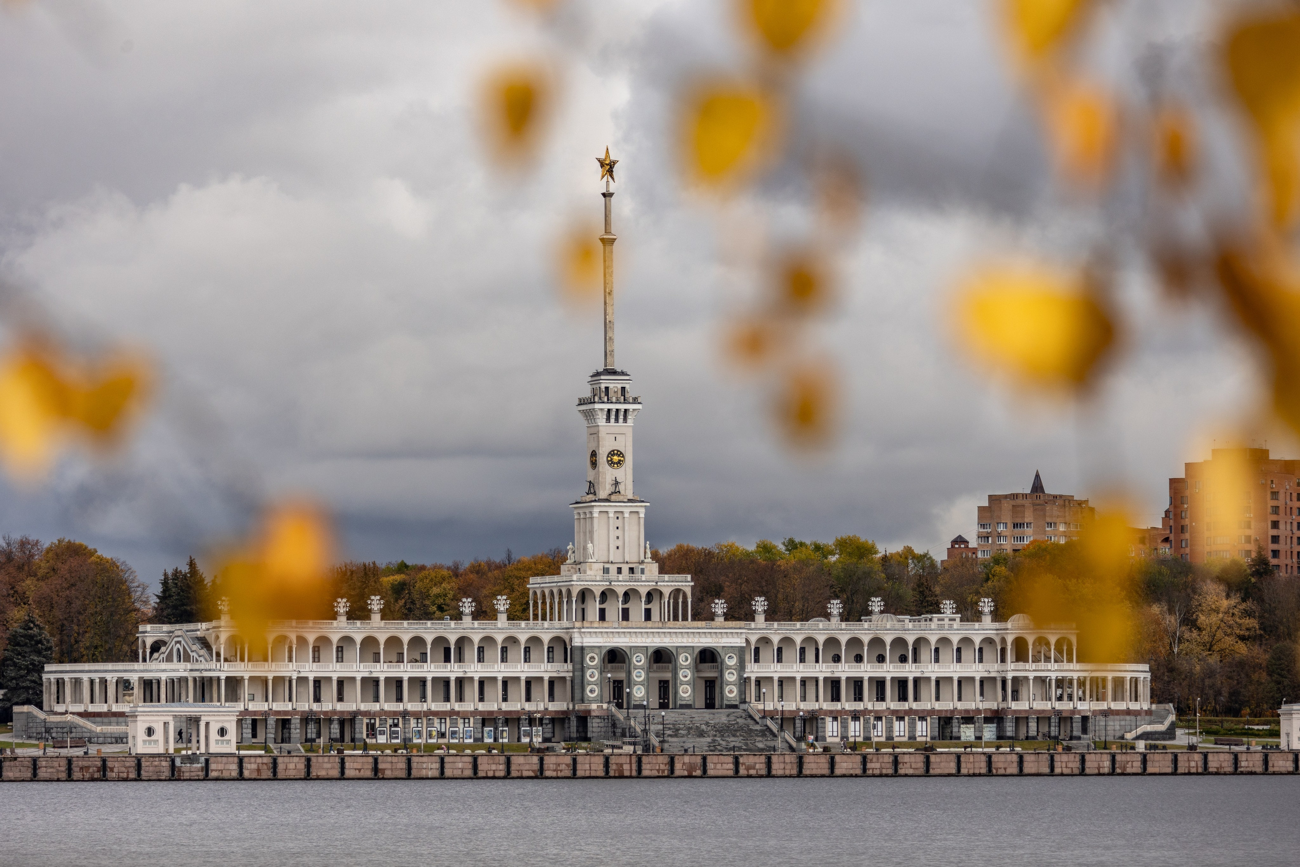 Здание северного речного вокзала на фоне желтых листьев осенью.