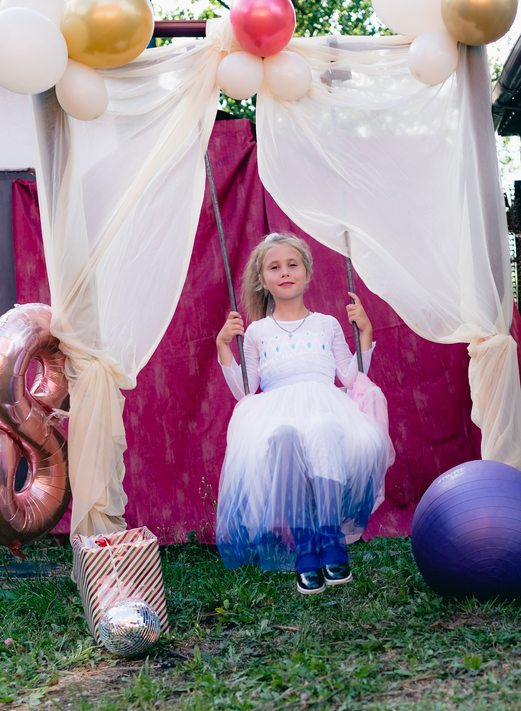 На фото девочка качается на качелях.