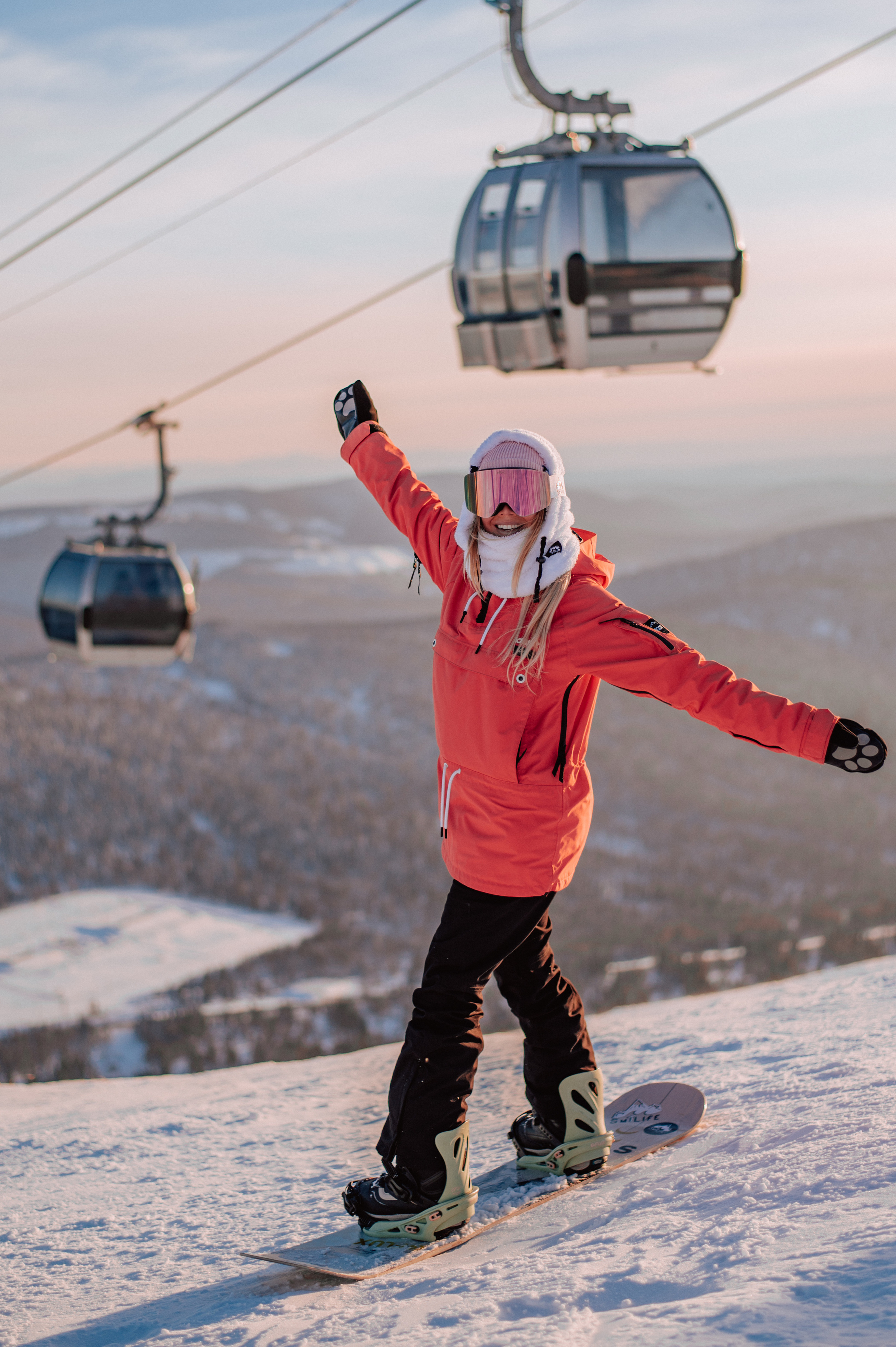 Сноубордистка на фоне подъемников