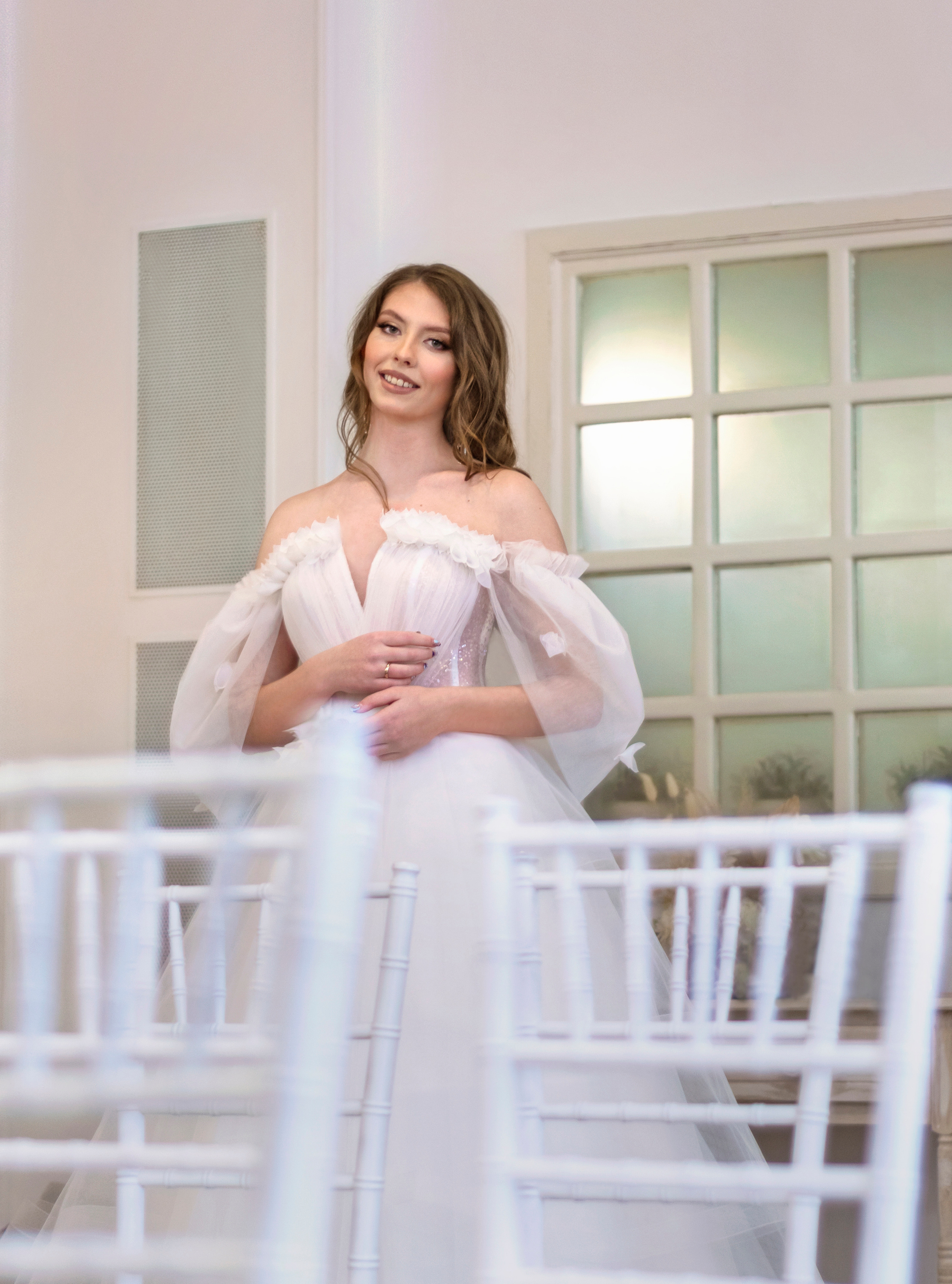 Невеста в белом красивом свадебном платье с открытыми плечами.