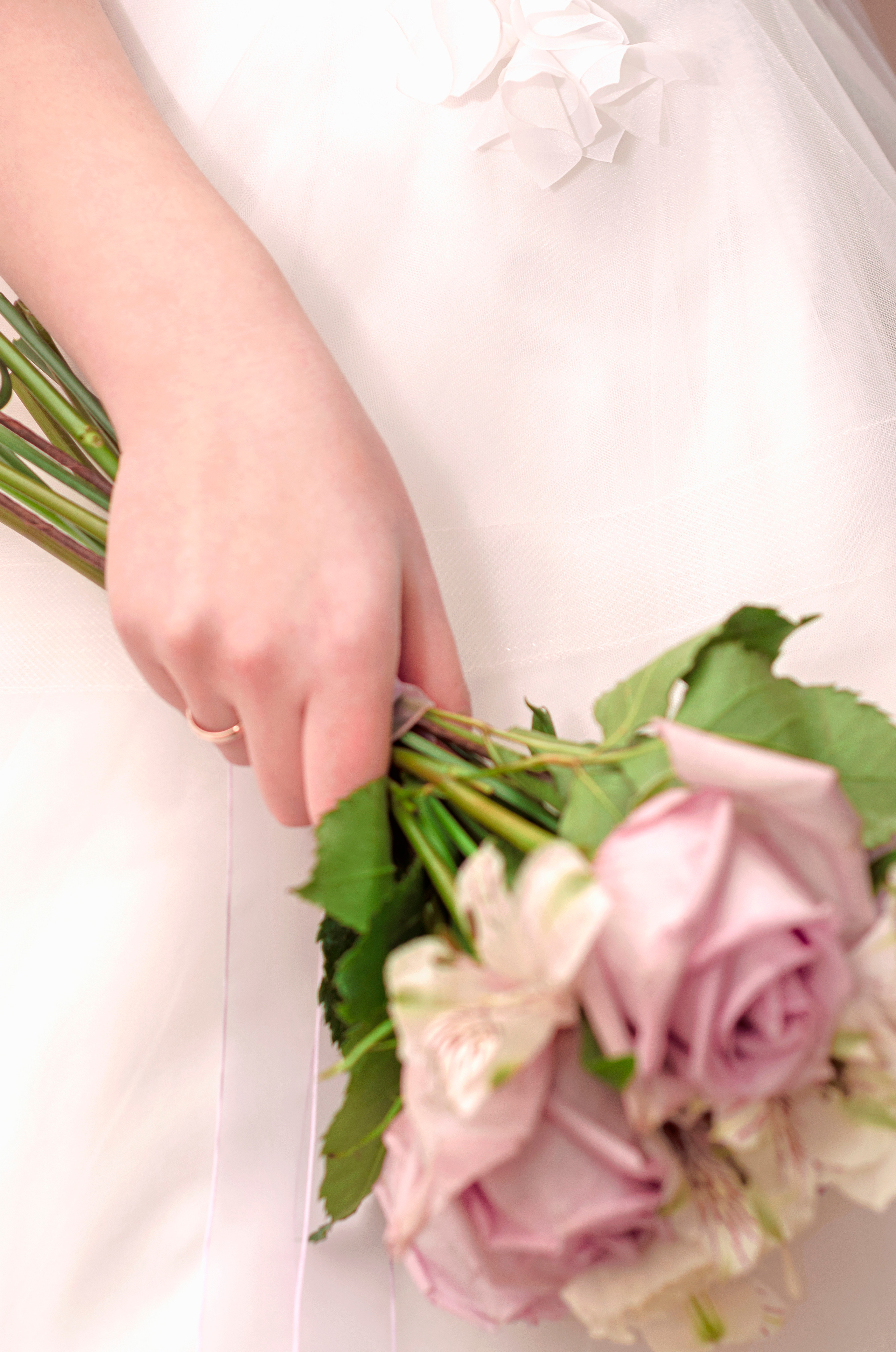 Фото розового букета невесты в опущенной руке девушки.