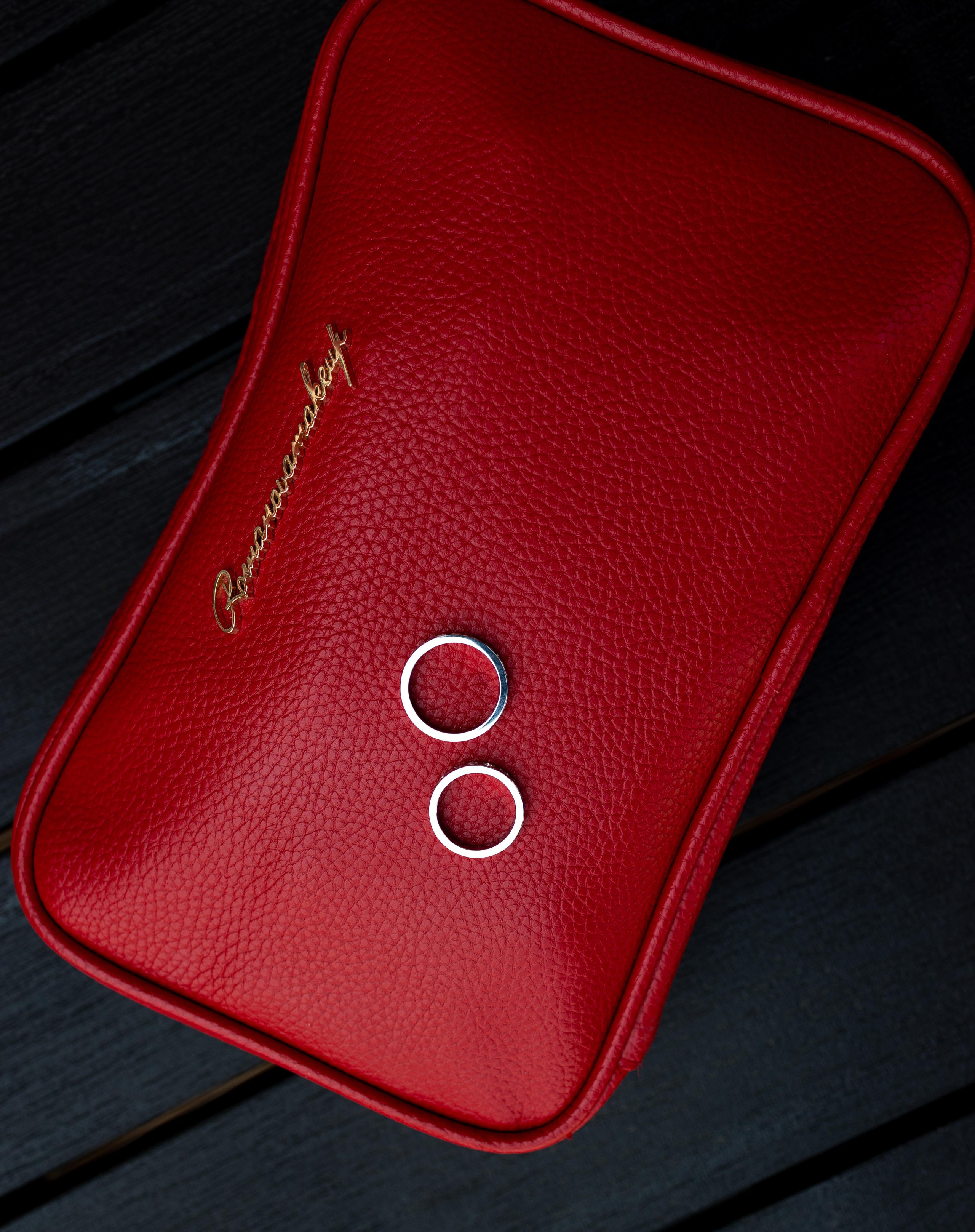 Свадебные кольца лежат рядомна красном кошельке 