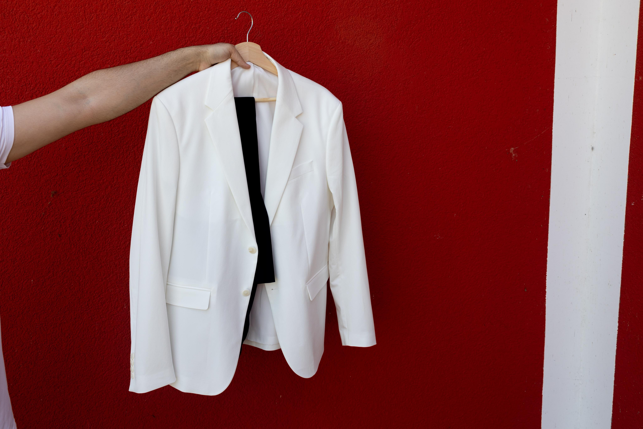 Жених показывает свой белый костюм после того ,как погладил 