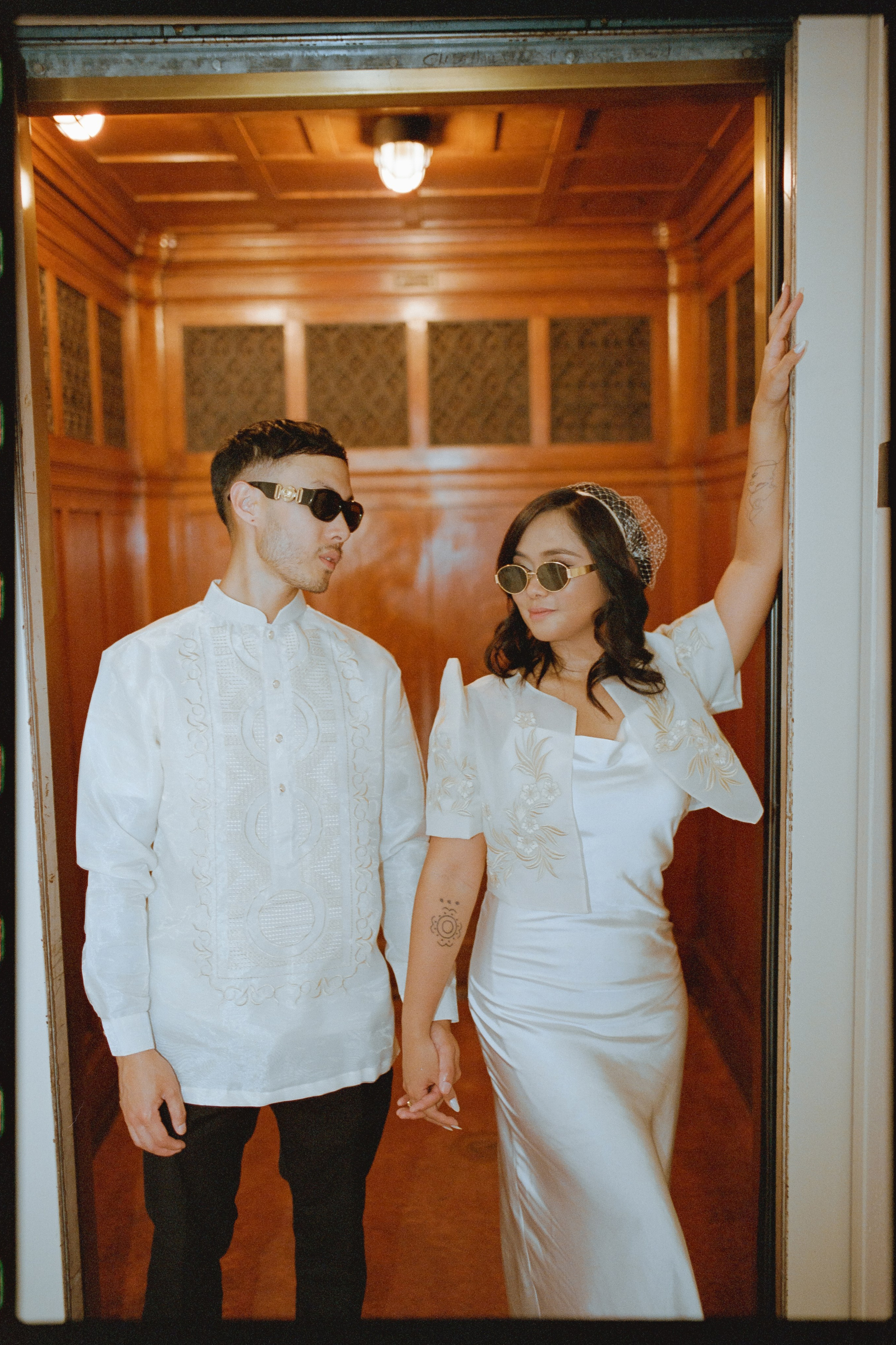 a cool photo of a bride and groom exciting elevator and wearing glasses