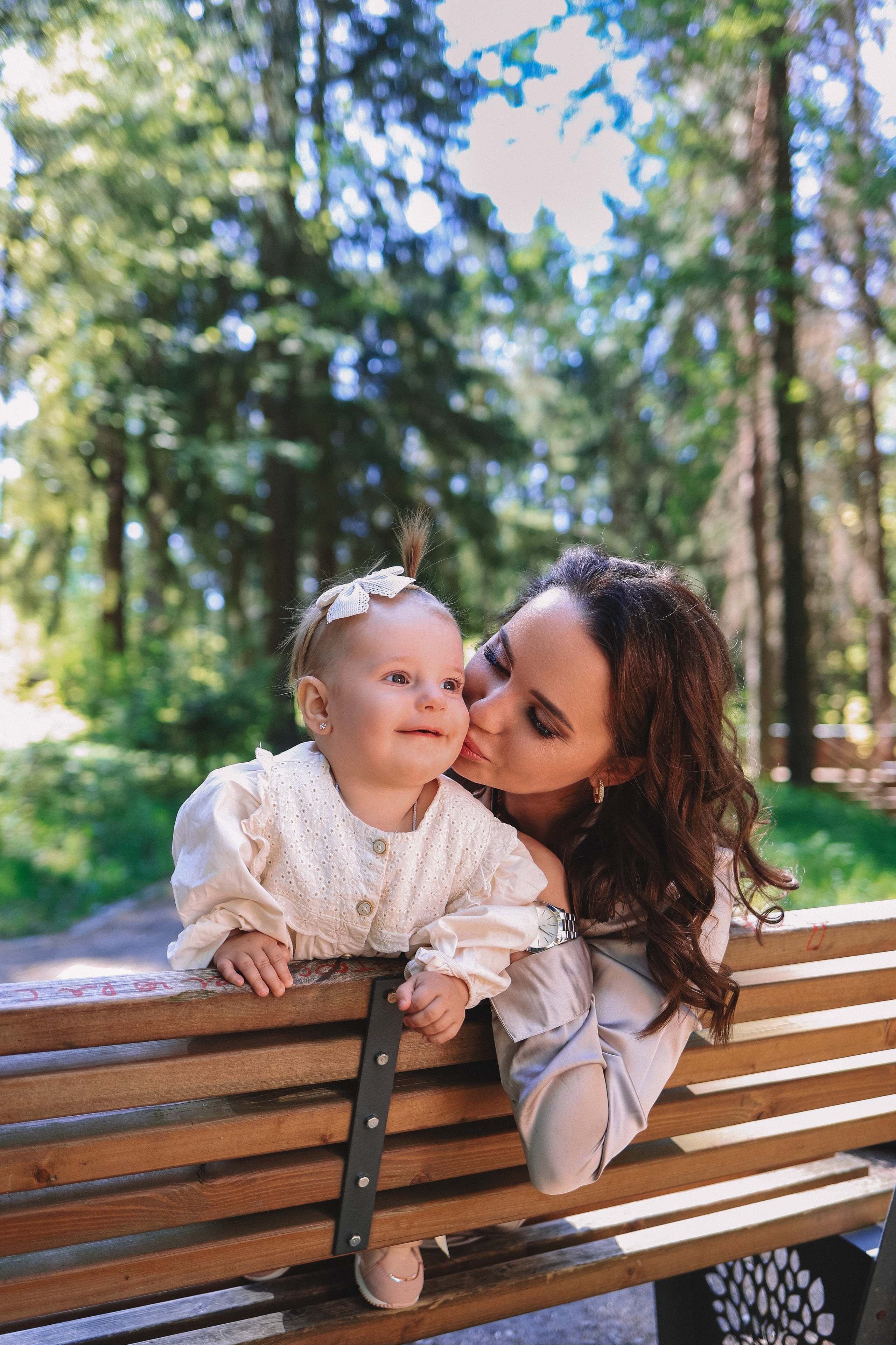 Счастливая мама с ребёнком на скамейке летом