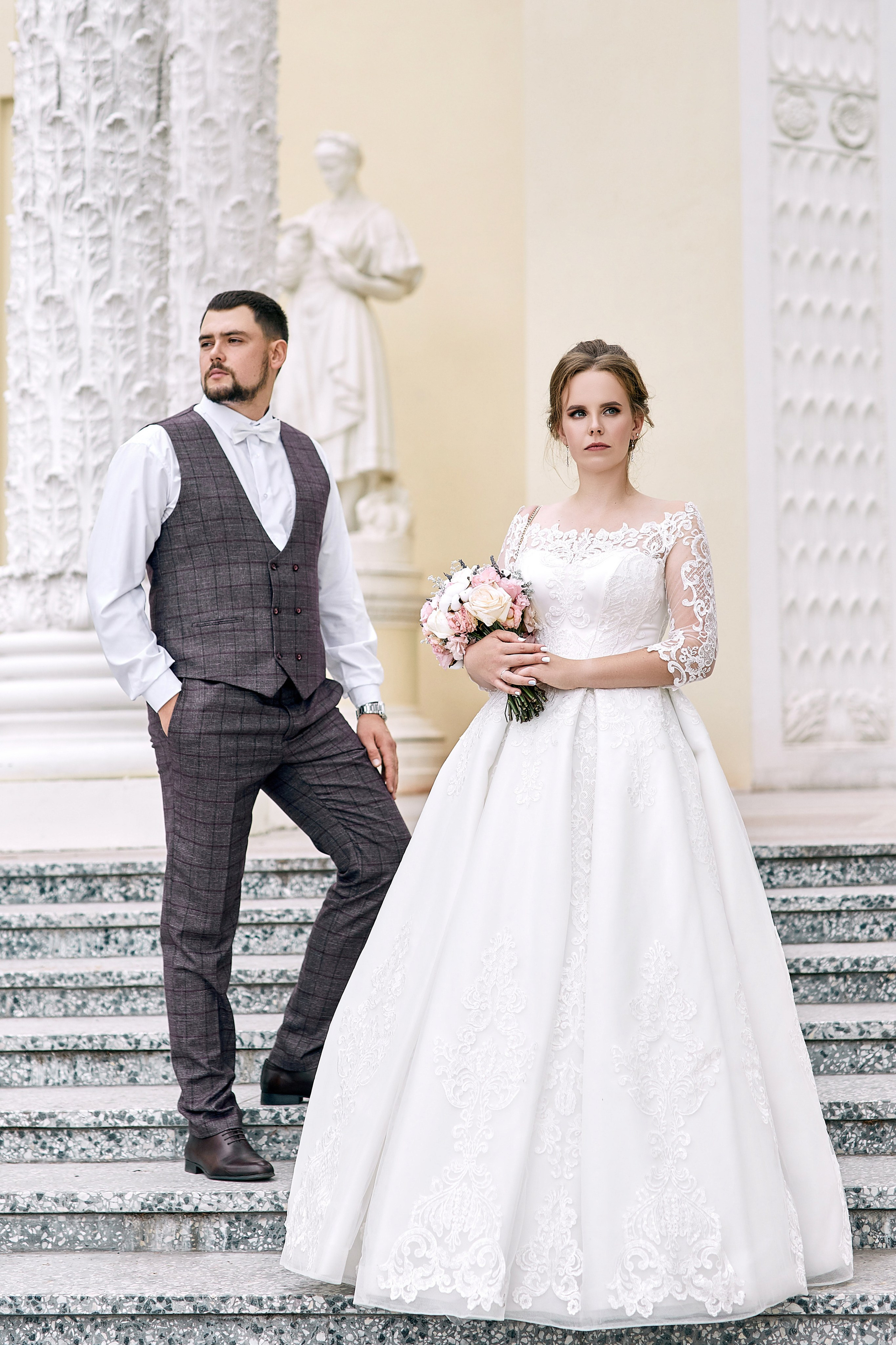 Фотограф в ЗАГС проводит фотосессию перед росписью на ВДНХ – фото жениха и невесты стоящих на фоне лестницы и колонн