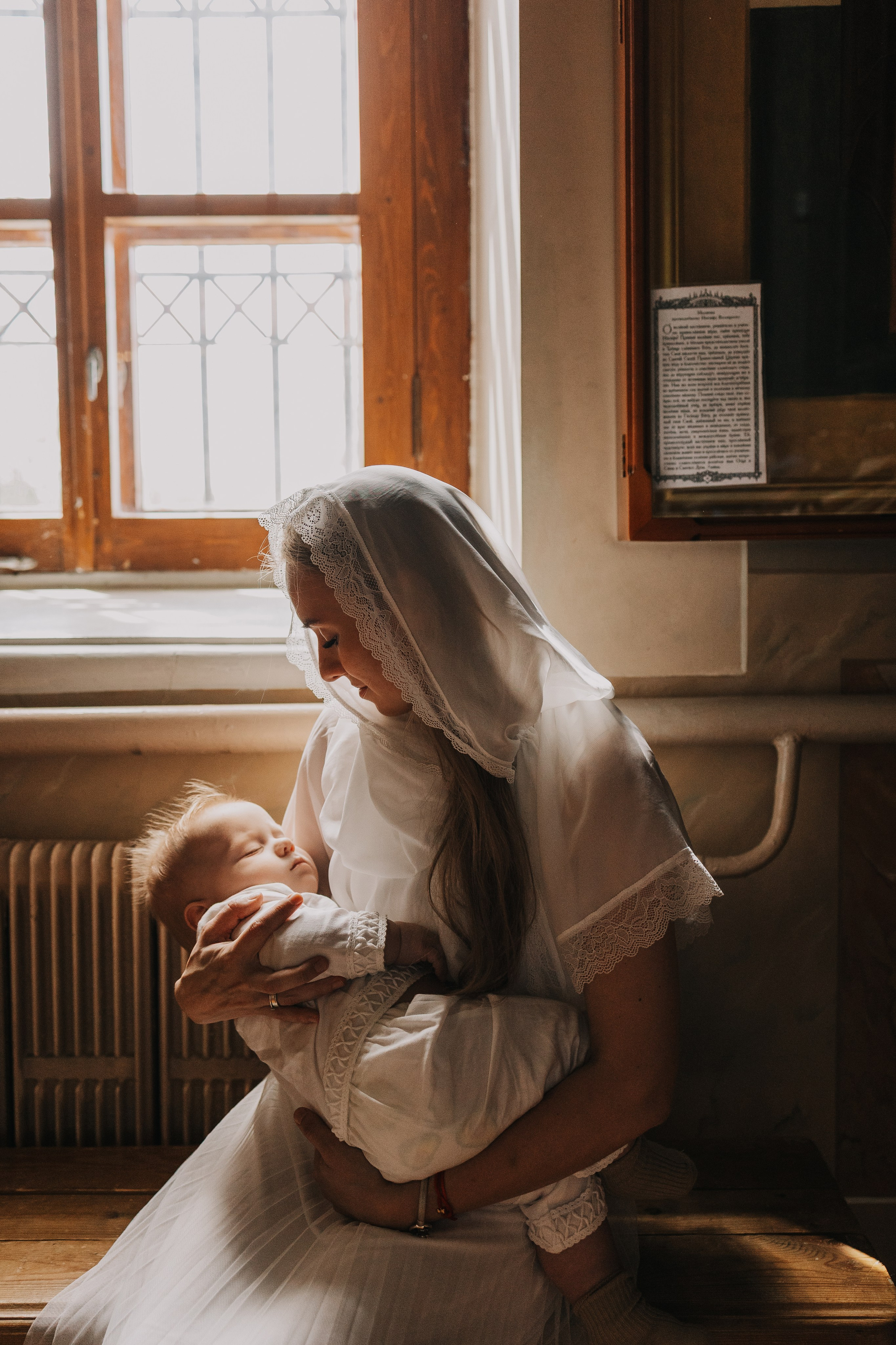 фотография в храме, крещение ребенка, мама держит на руках ребенка