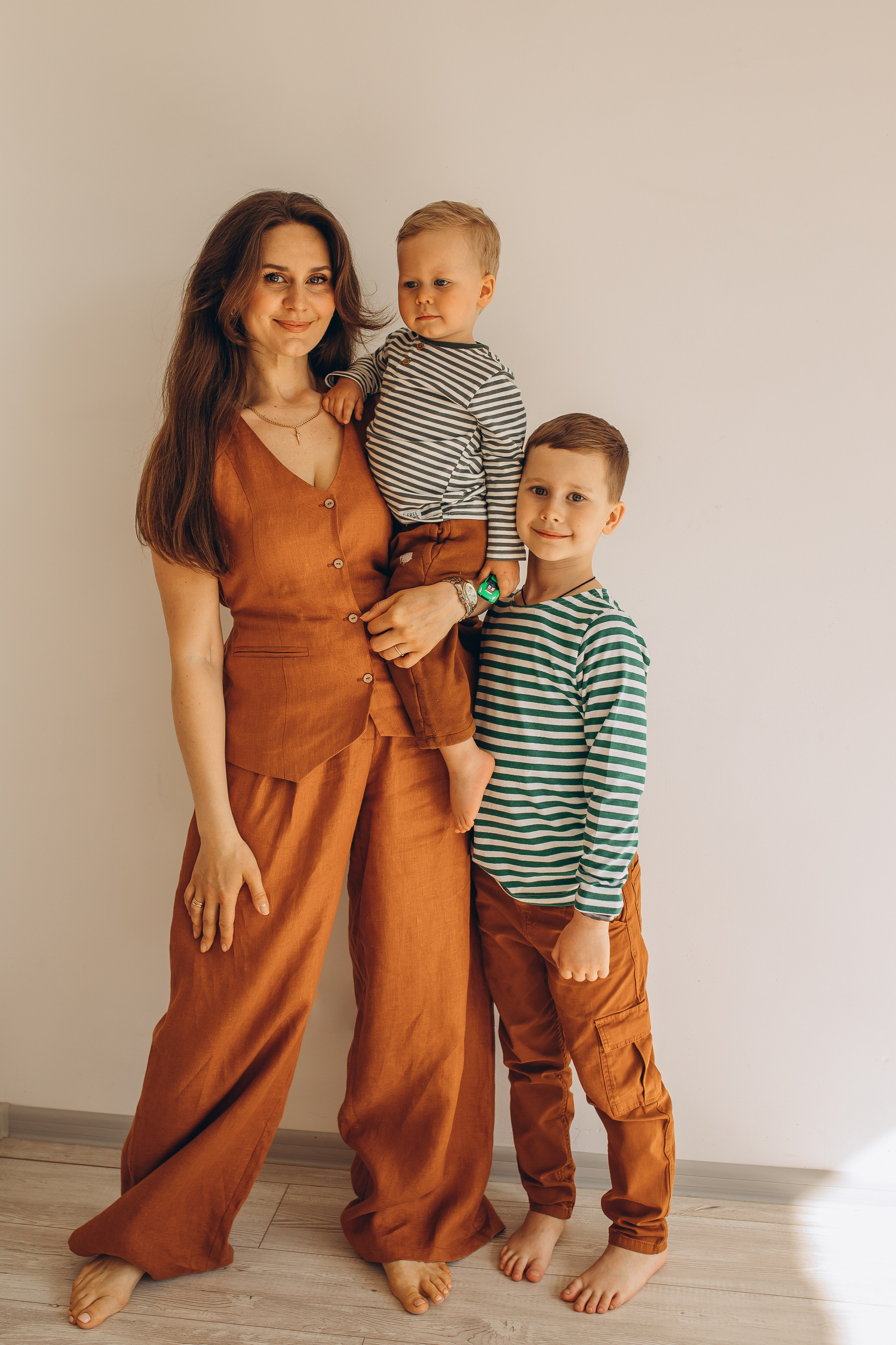 Счастливая мама в оранжевом комбинезоне на фотосессии с сыновьями в светлом интерьере. Детский и семейный фотограф Маруся Самылкина в Санкт-Петербурге.