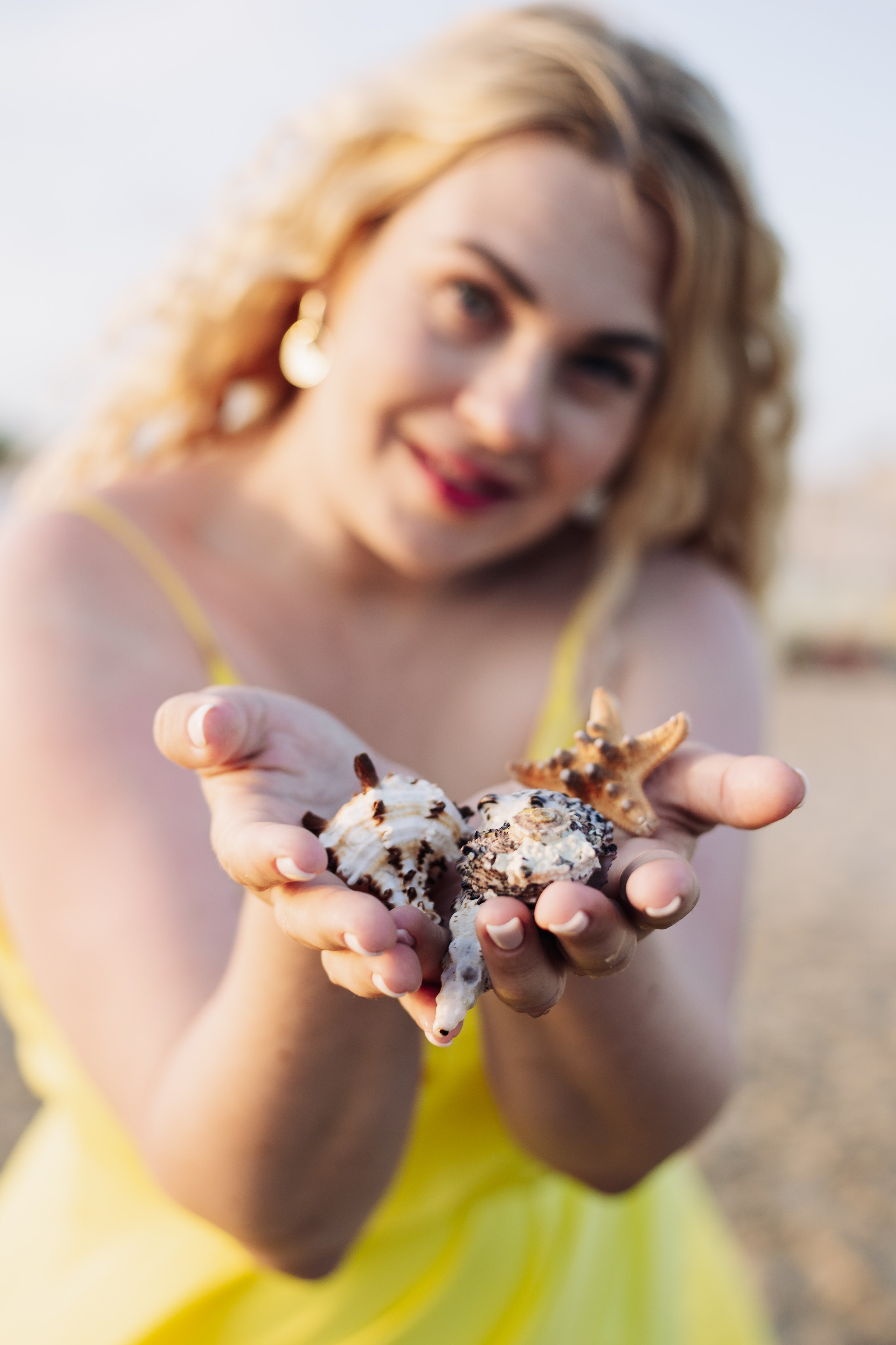 Фотосессия на пляже в Анапе: девушка держит в руках морские раковины
