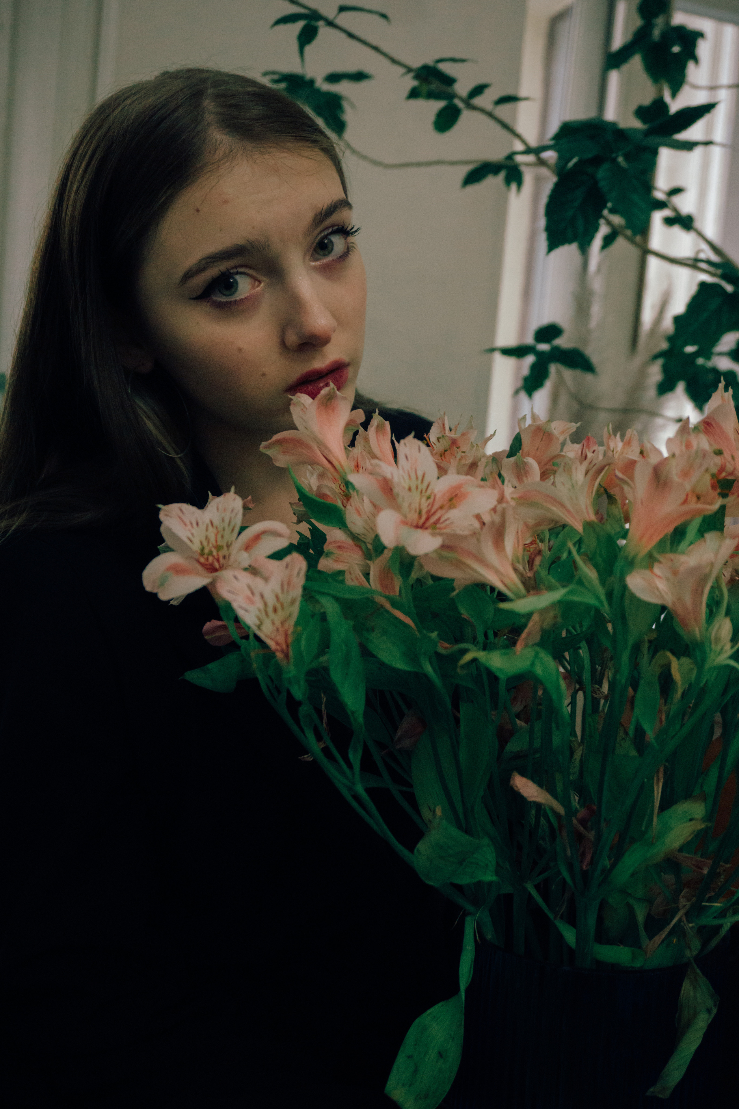 Фотография молодой девушки в студии с цветами и грустным лицом