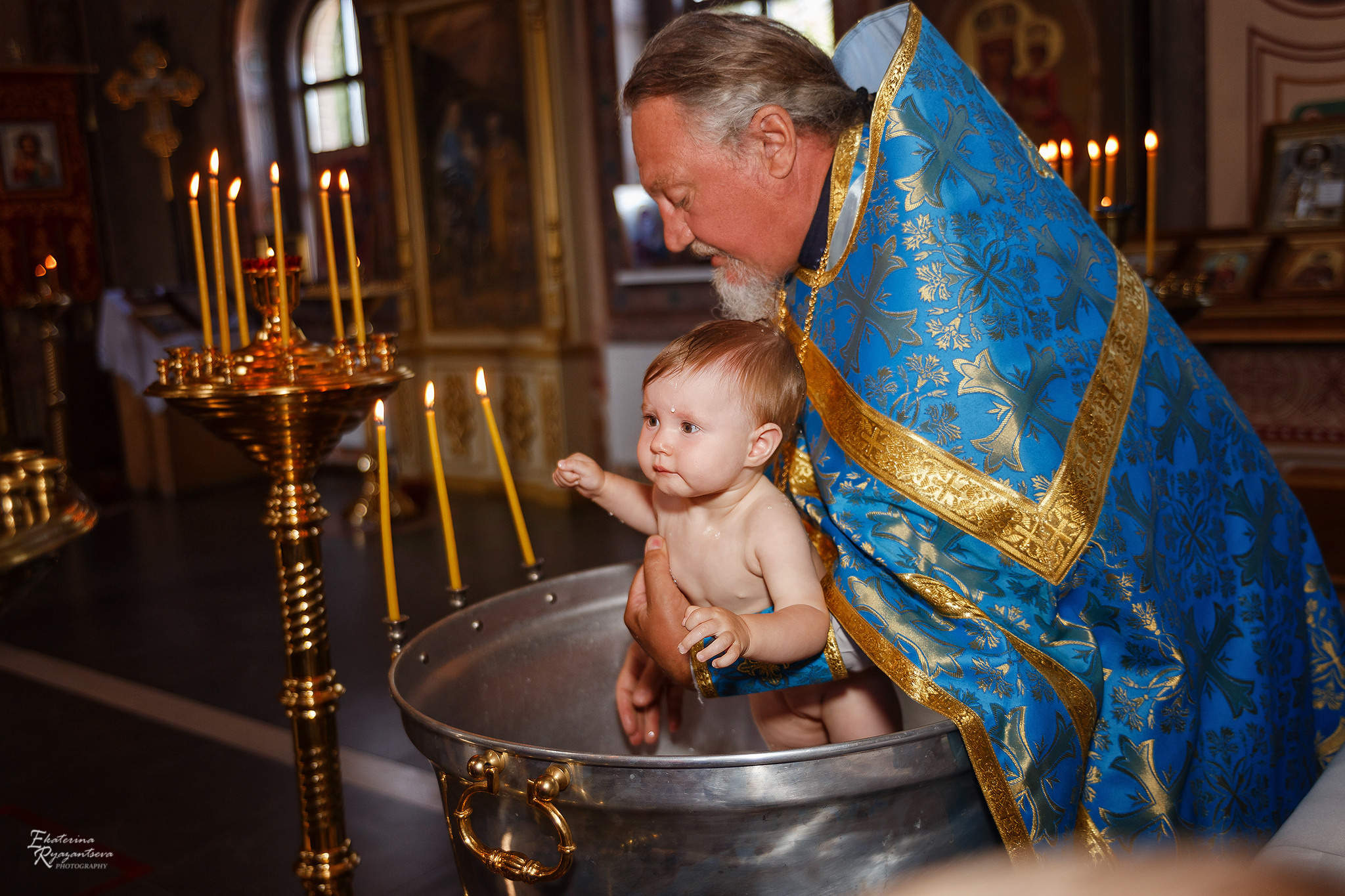 Крещение ребенка. Батюшка окунает малыша в купели