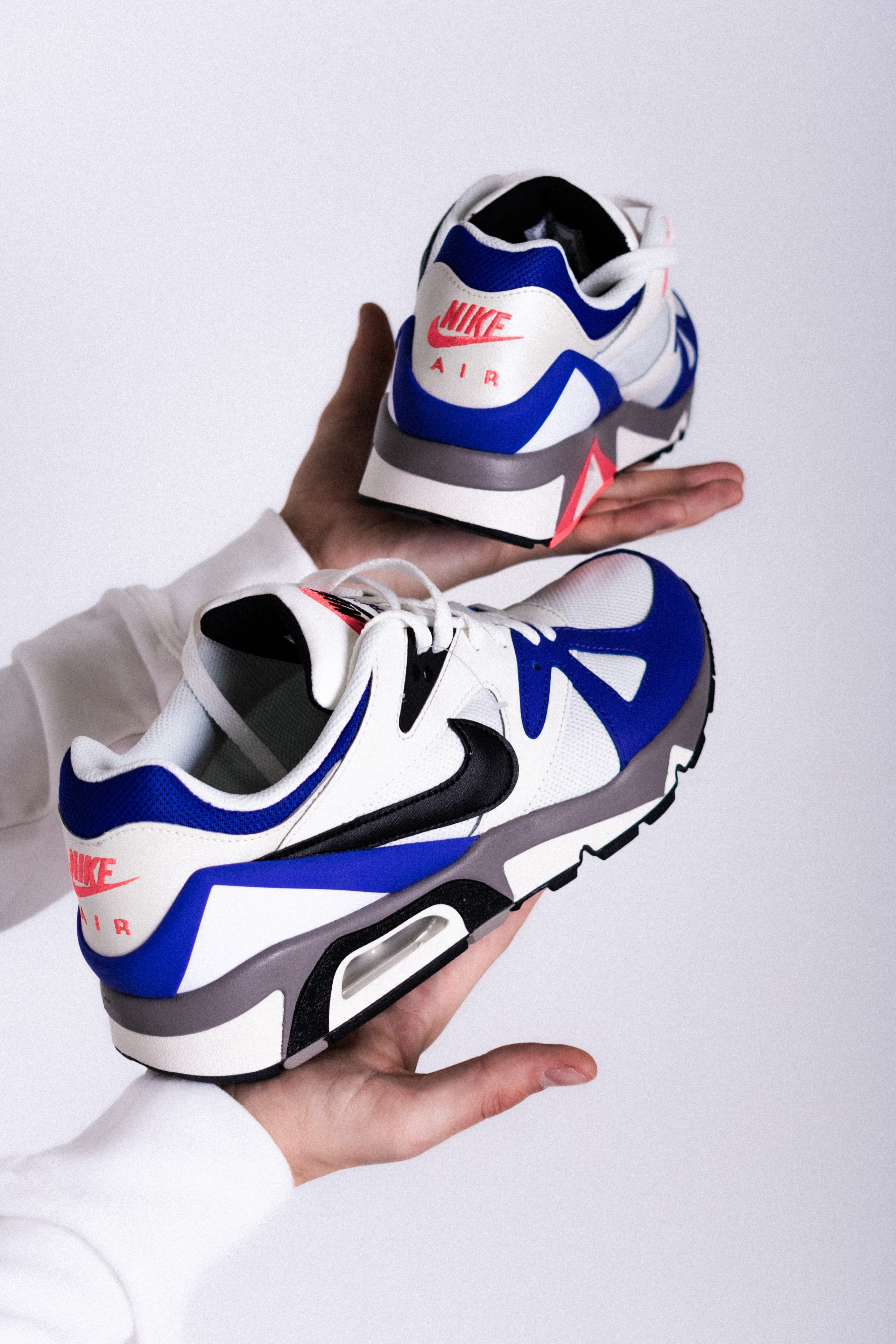 Кроссовки nike держат в руках на белом фоне