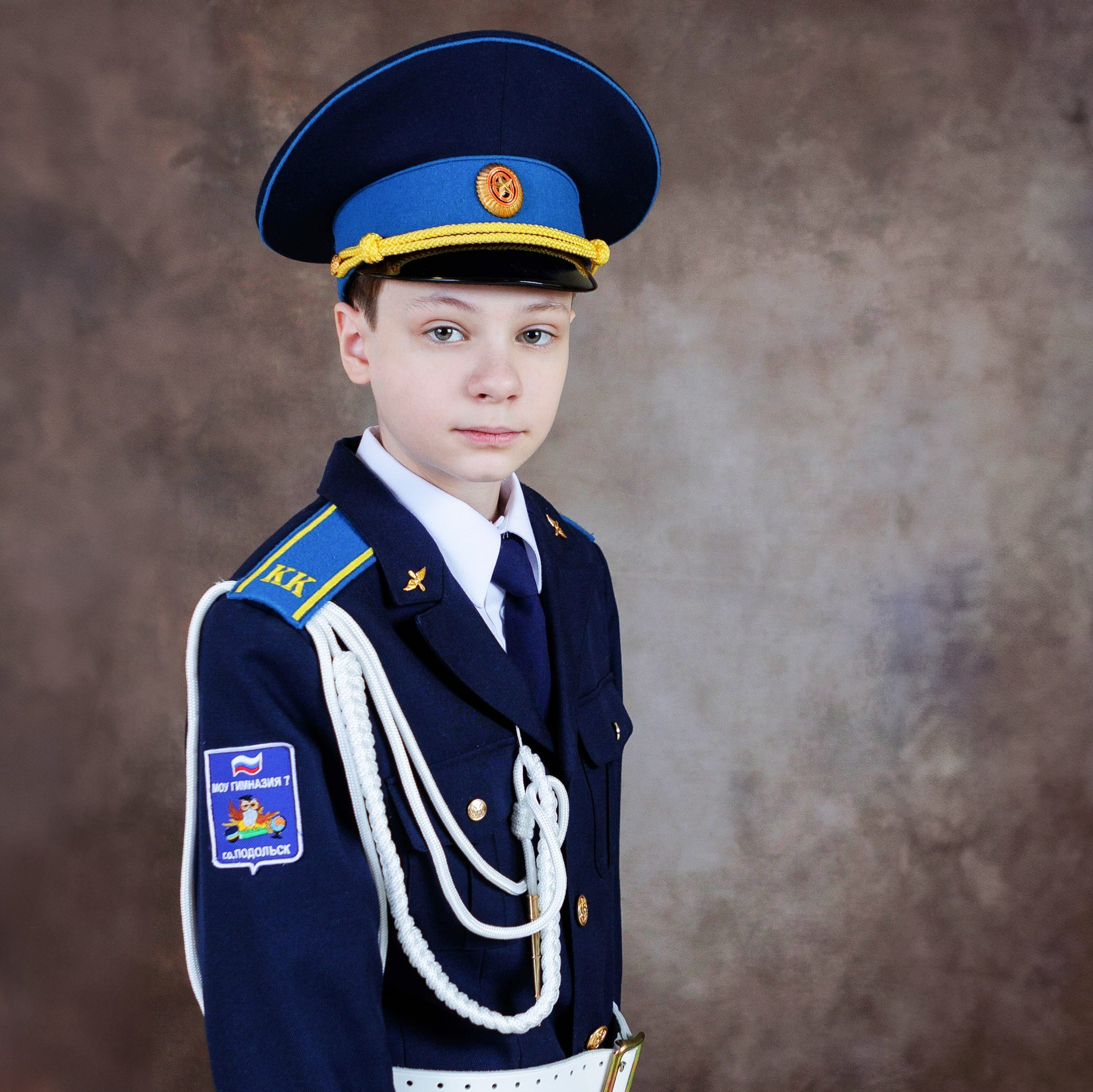 Школьный портрет девочки в форме на фоне книжных полок.