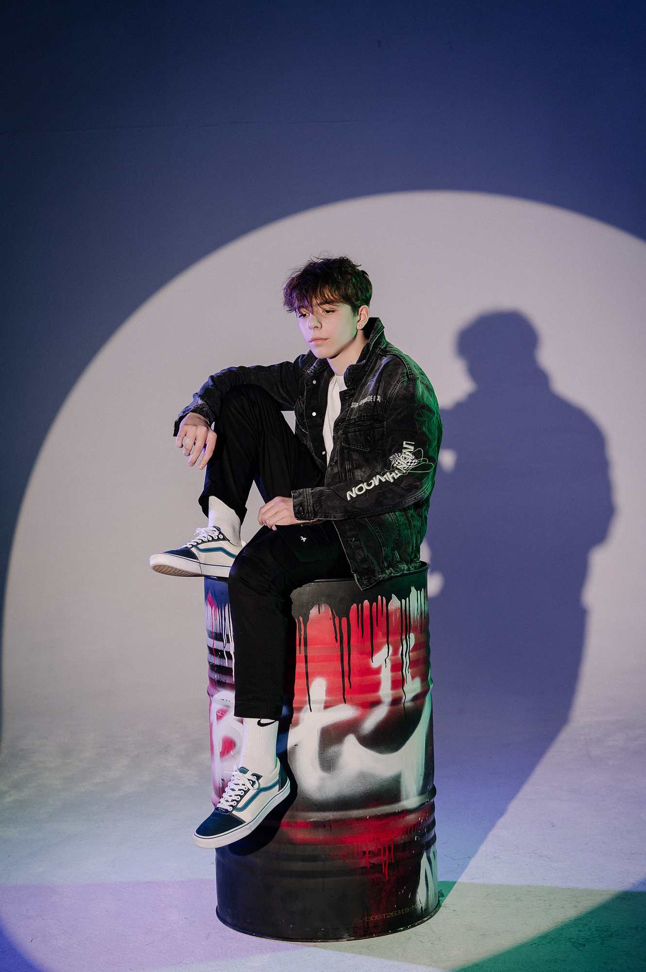 Ученик 9 класса сидит на железной бочке в рамке видео света. Работа школьного фотографа студии Вышка в Москве.