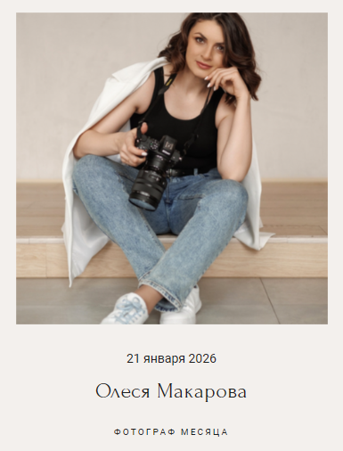 Девушка с тёмными волосами в чёрном топе и джинсах сидит на ступеньках с фотоаппаратом в руках, на плечах — светлый плащ. Атмосфера спокойная, стильная.