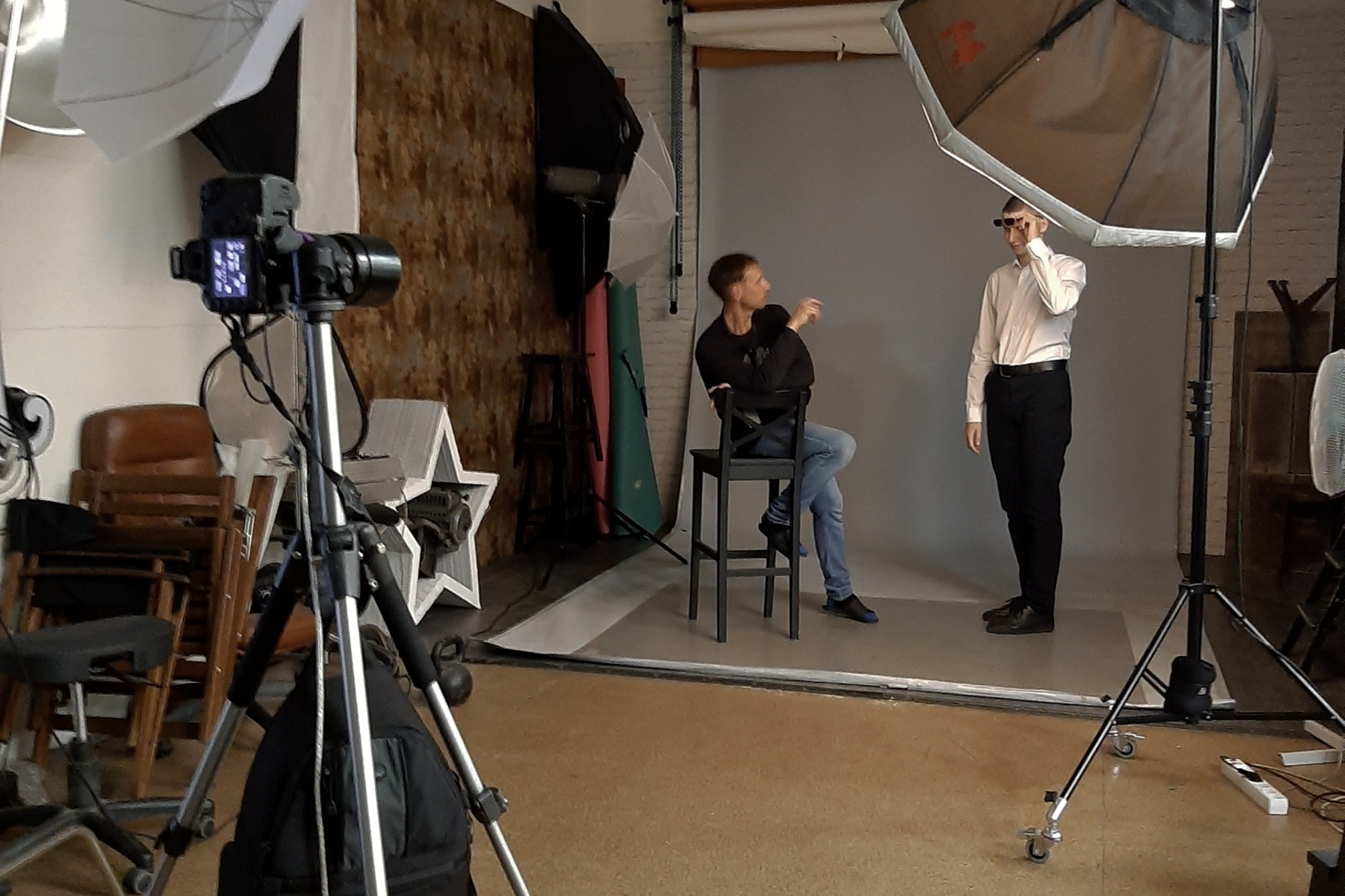 Фотограф в фотостудии показывает модели позирование в положении сидя..