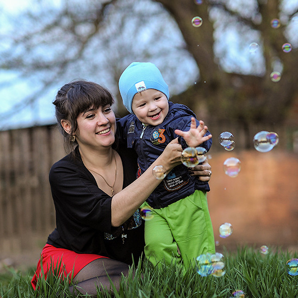 лений день мама с ребенком на лужайке частного дома пускают мыльные пузыри