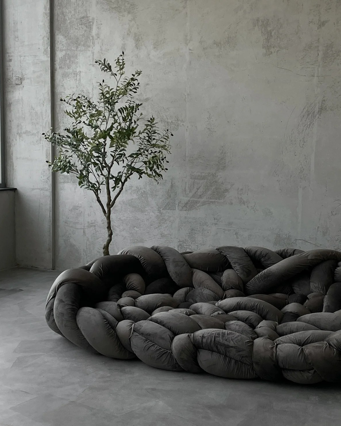 Зал с бетонными стенами и серым огромным диваном для фотосессии