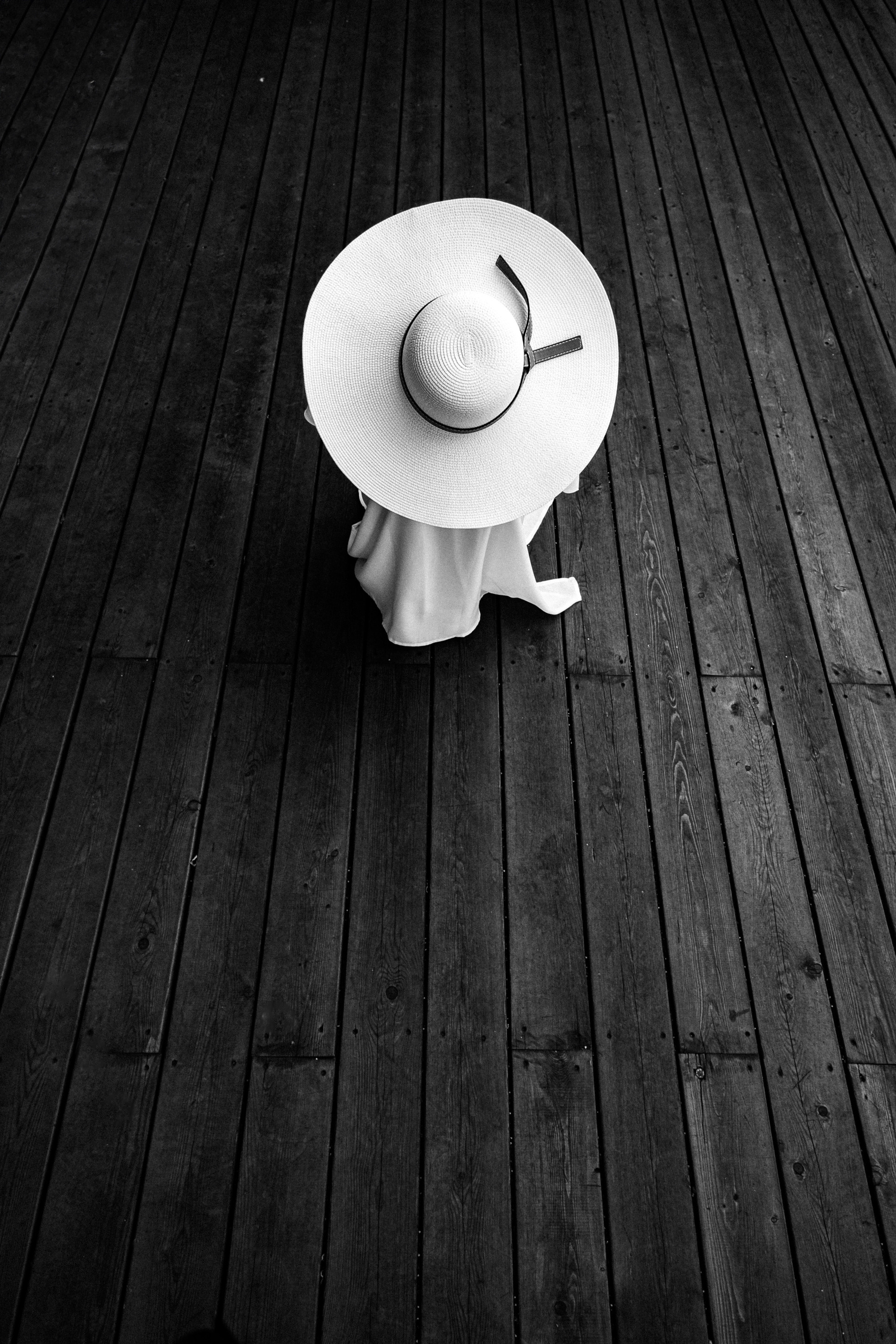 Девушка в белой шляпе сидит на полу.