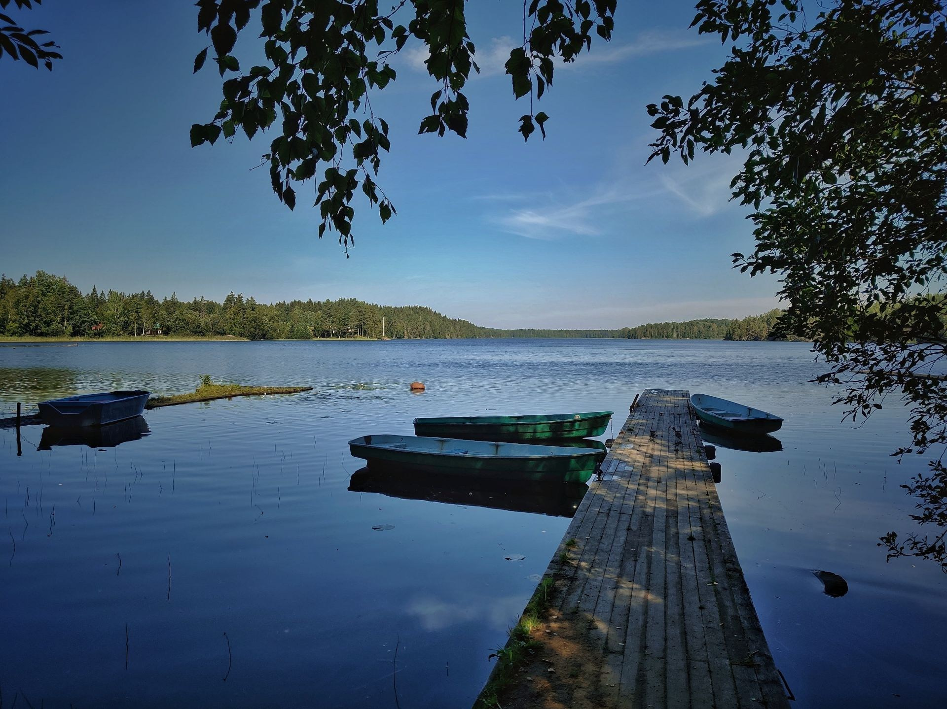 Озеро Пайкъярви, лодки у деревянного причала, тени деревьев и ясное небо