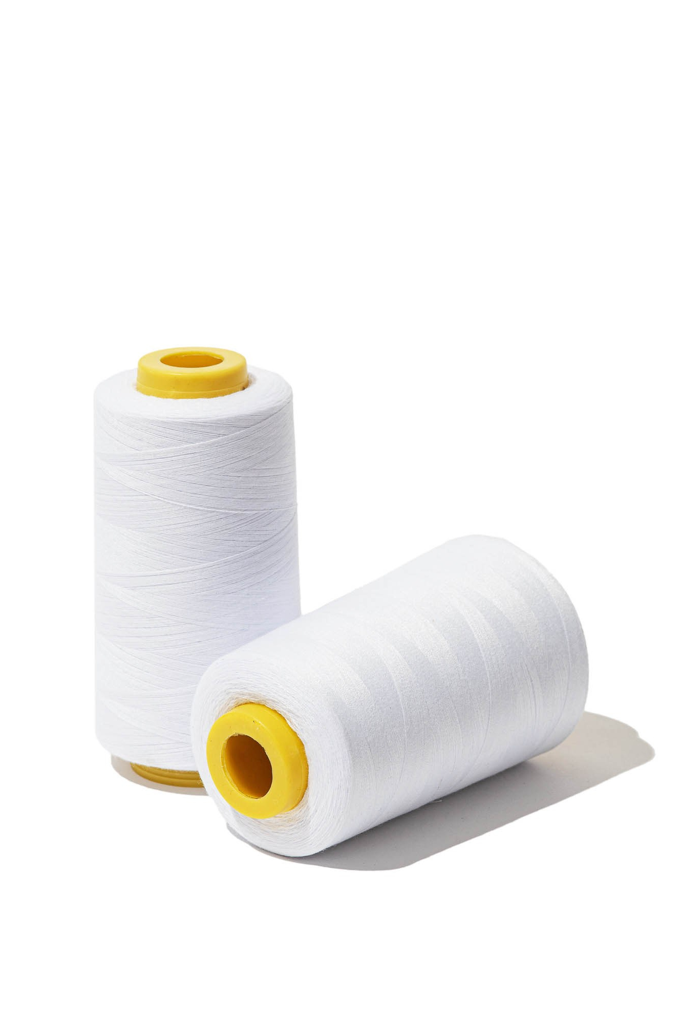 Белые катушки ниток на нейтральном фоне — демонстрация каталожной съемки текстиля.