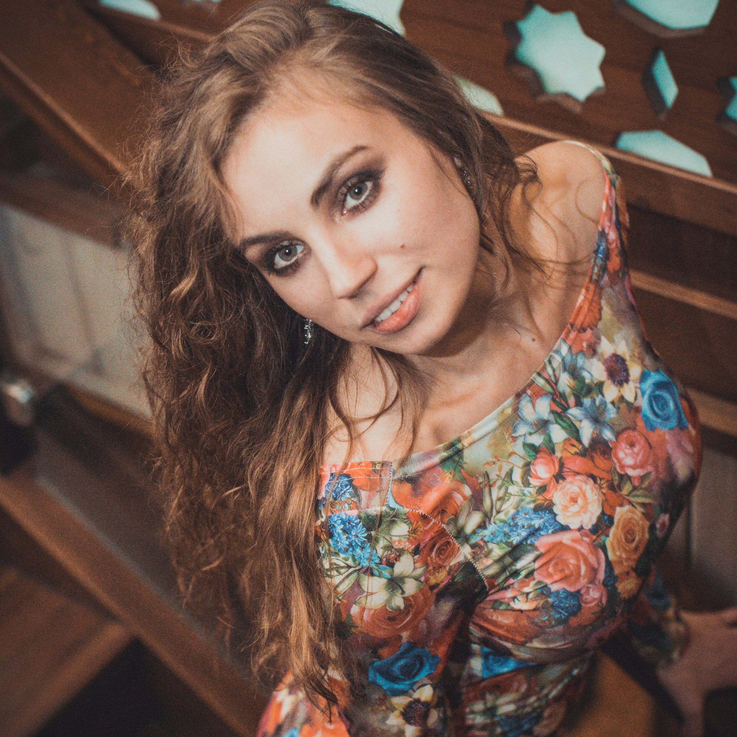 красивая девушка с кудрявыми, русыми волосами, позирует снизу вверх с приятным выражением лица