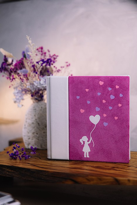 Фронтальное фото готовой фотокниги в интерьере. Сочетание премиальной замши и кожи в оформлении детского архива.