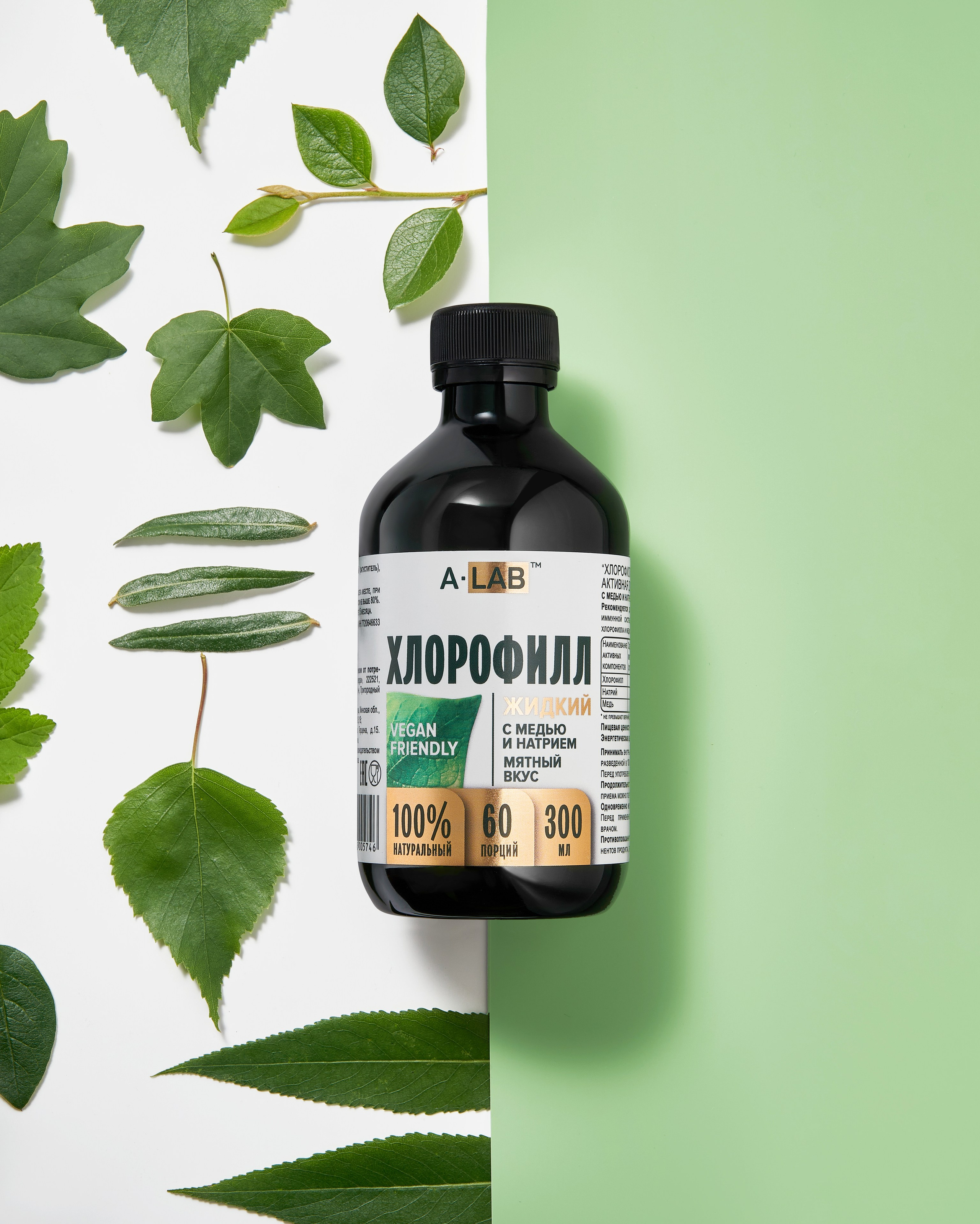 Банка с хлорофиллом лежит на светло-зеленом фоне, из-под которого выглядывают зеленые листья