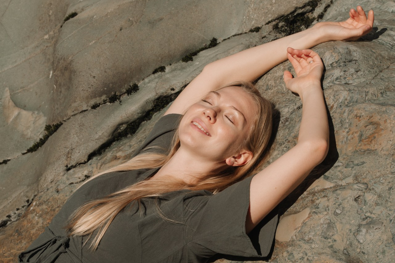 Портретный снимок девушки лежащей на камне