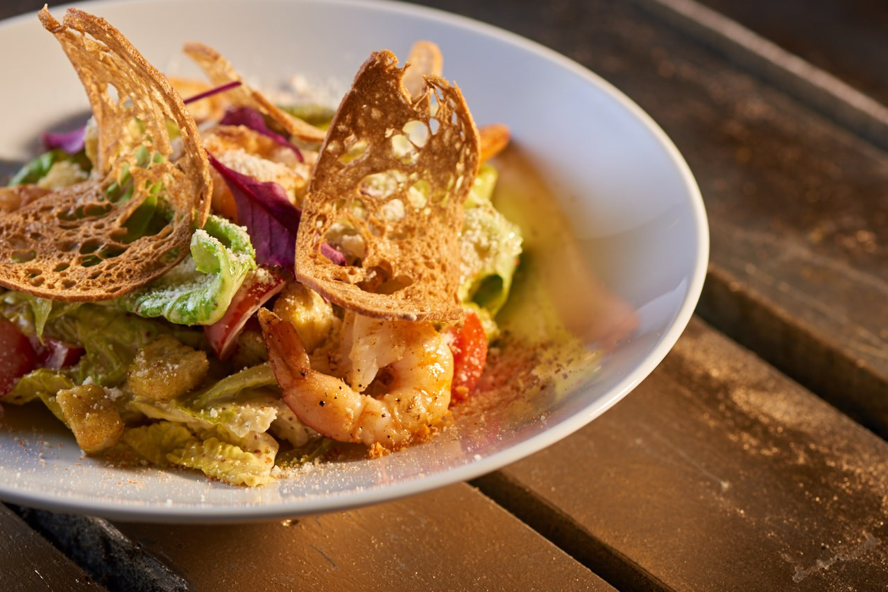 Фуд-фотография блюда с мясом, овощами и зеленью, снятого на деревянной поверхности