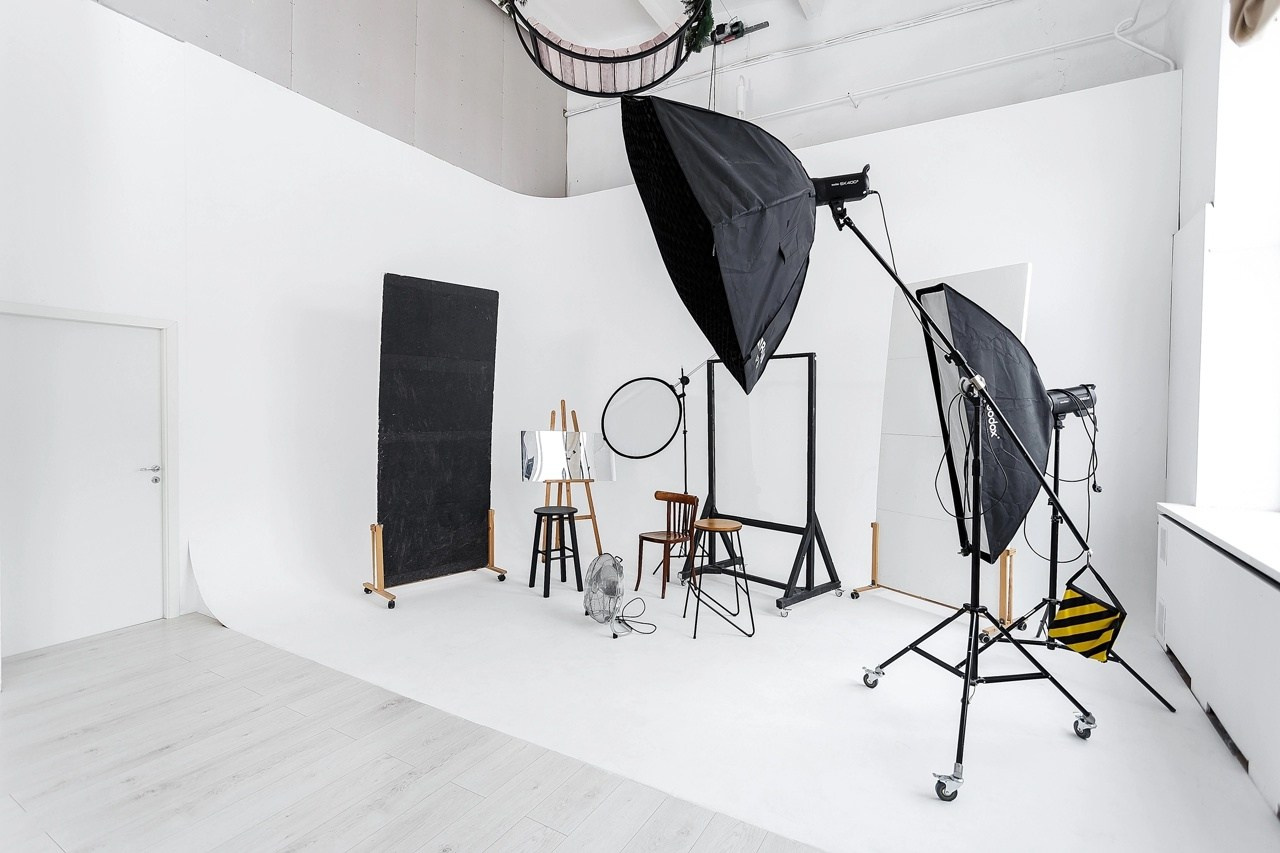 Новогодний интерьер белого зала студии Точка: украшенная елка с гирляндами и диван для праздничной фотосессии