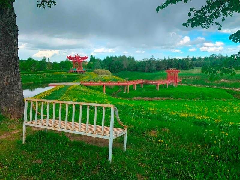 Белая скамейка и красные мостики в парке